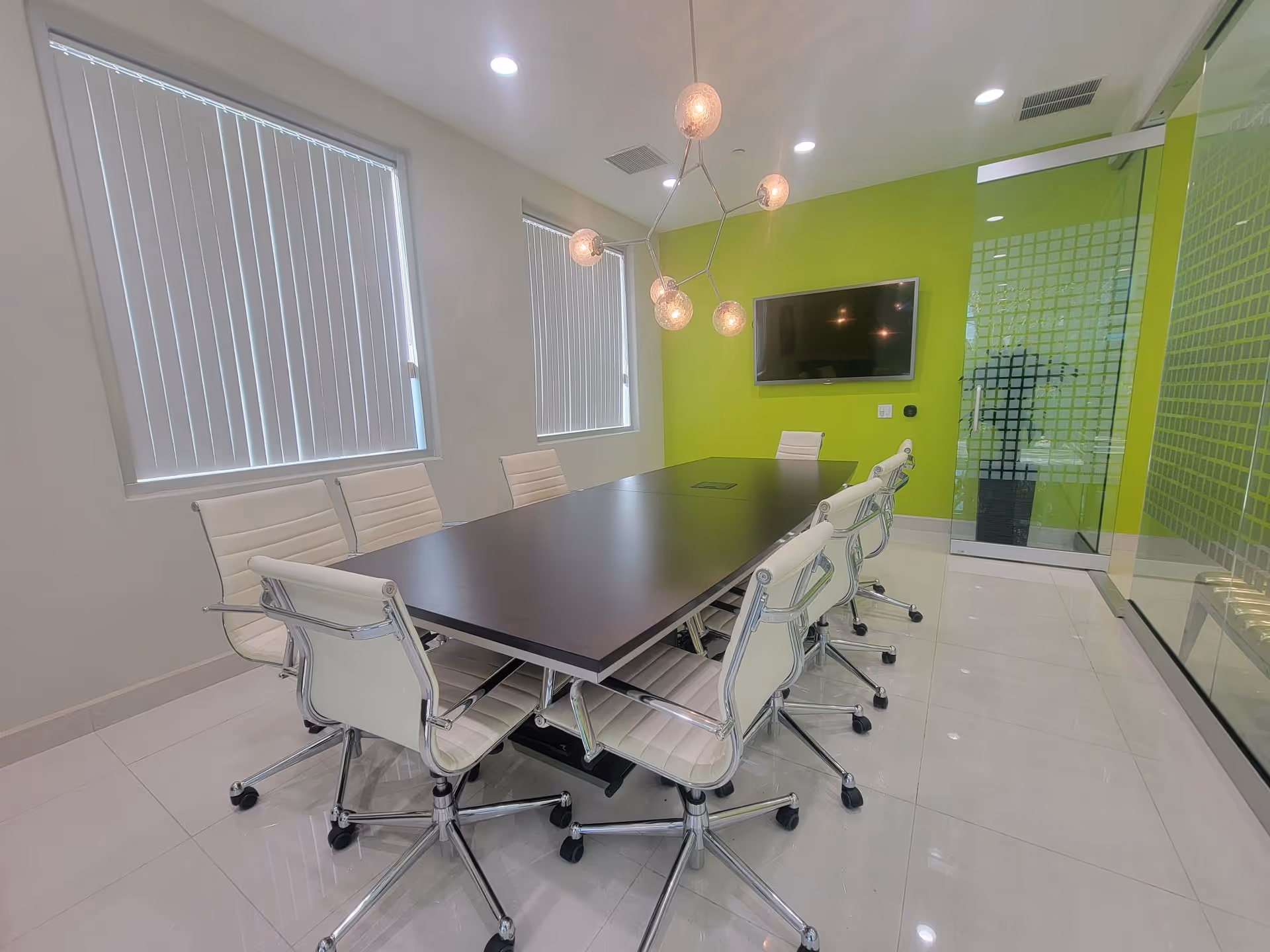 Modern conference room with a long table, white chairs, and lime green accent wall.