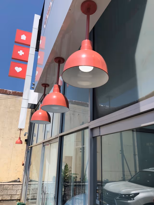 Exterior storefront of Elite Home Health Care with red pendant lights along glass windows.