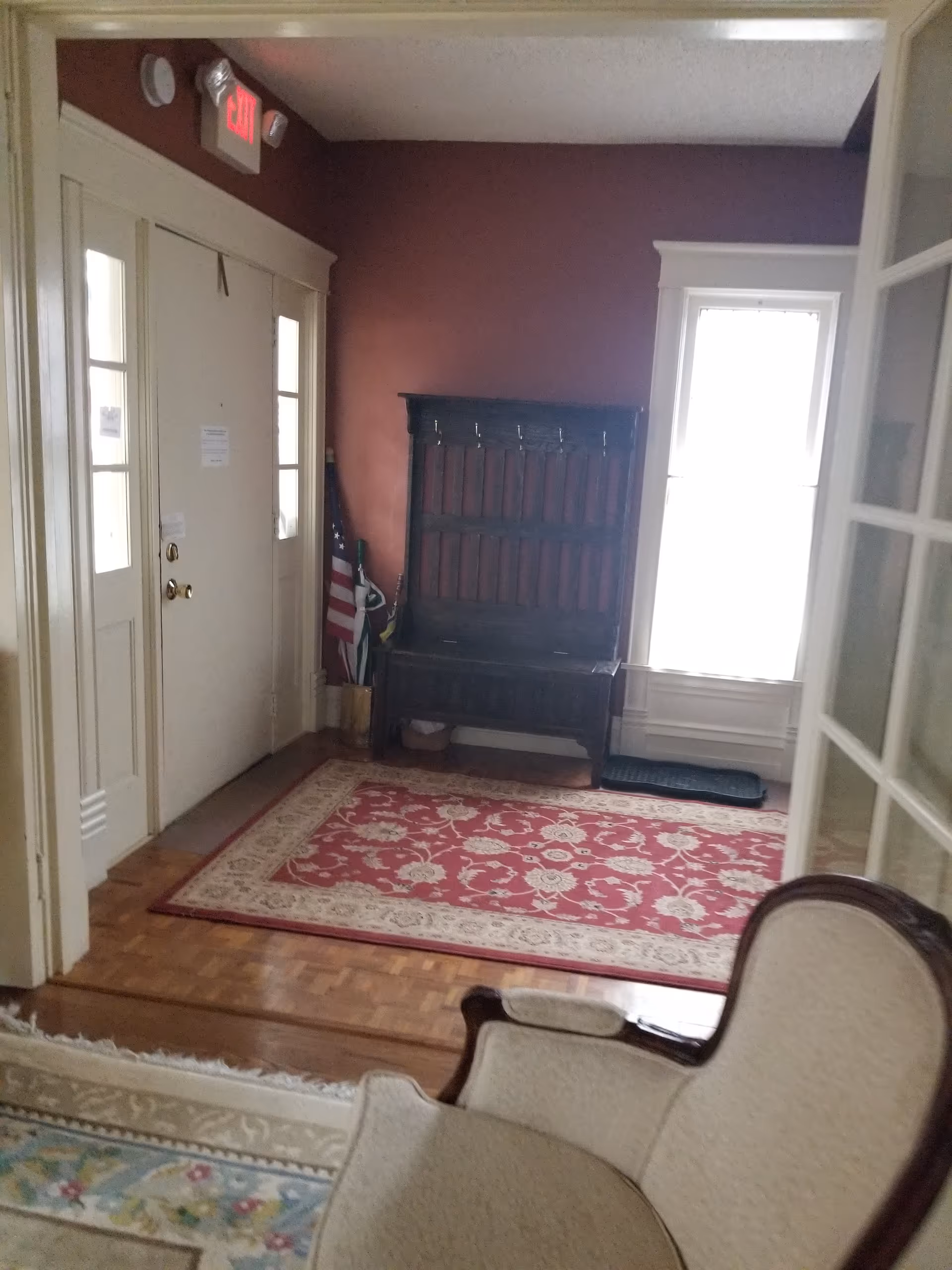 Entry hall with door, bench, coat rack, rug, and bright window light