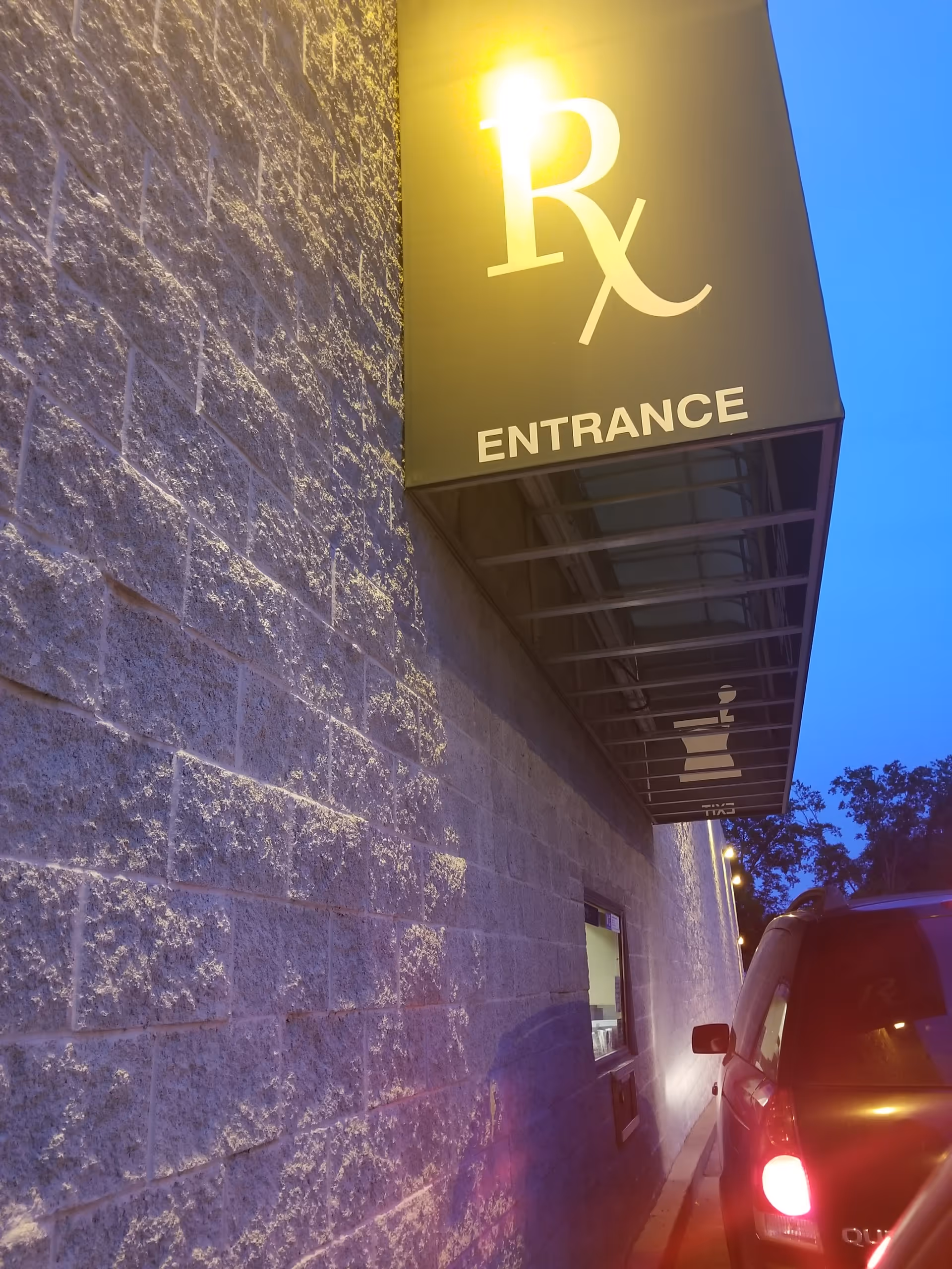 Exterior view of Kroger Pharmacy building with illuminated Rx Entrance sign at dusk.