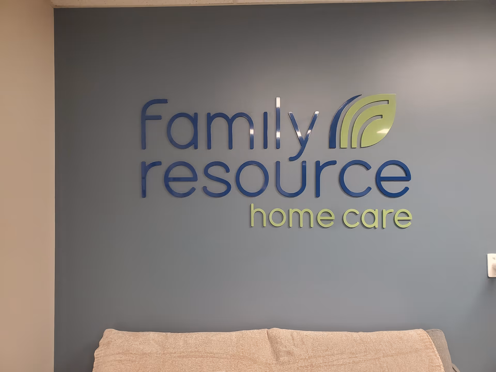 Blue wall shows Family Resource Home Care logo with a couch in the foreground.