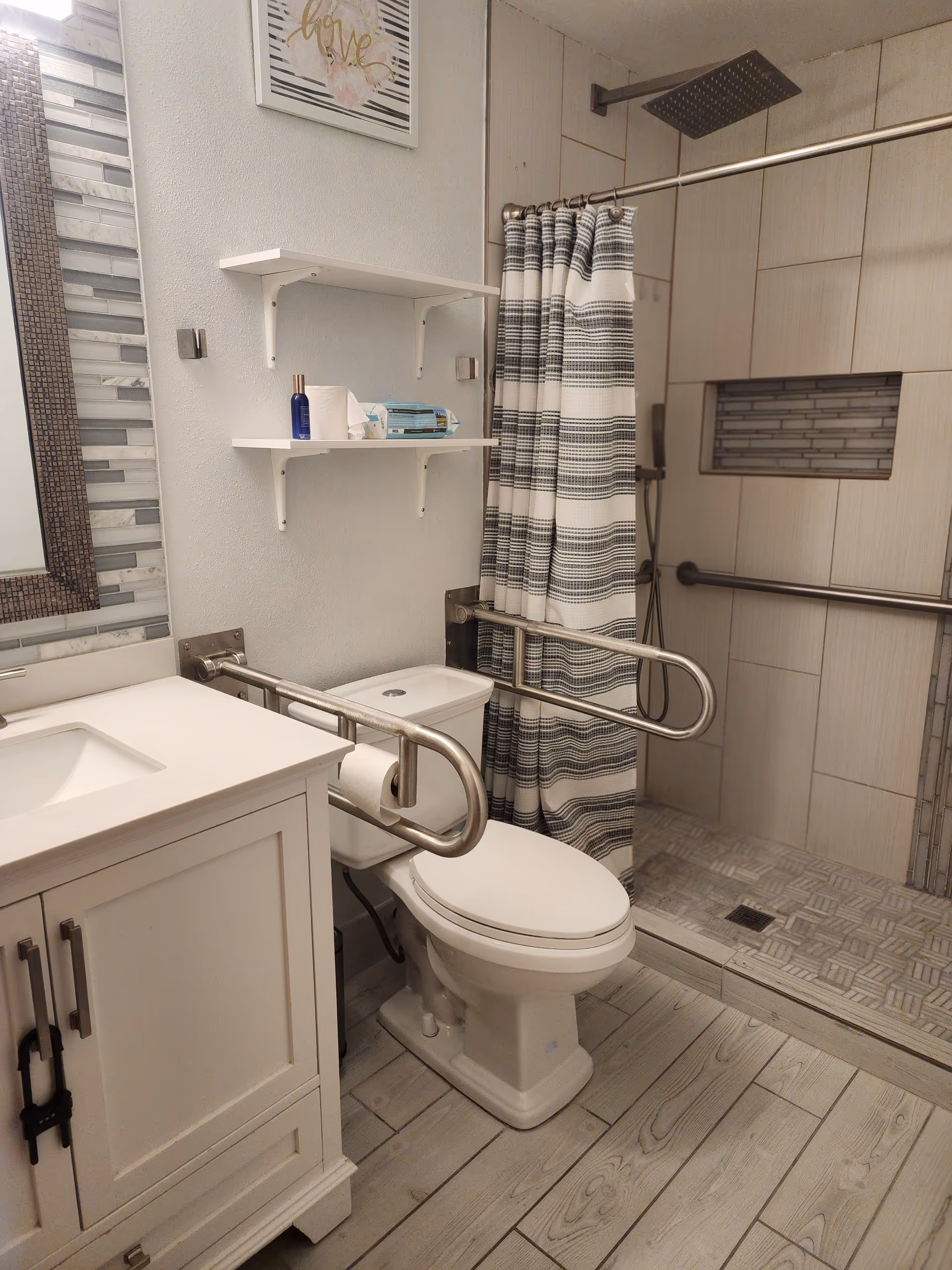 Accessible bathroom with walk-in shower, toilet, sink, grab bars, and shower curtain.