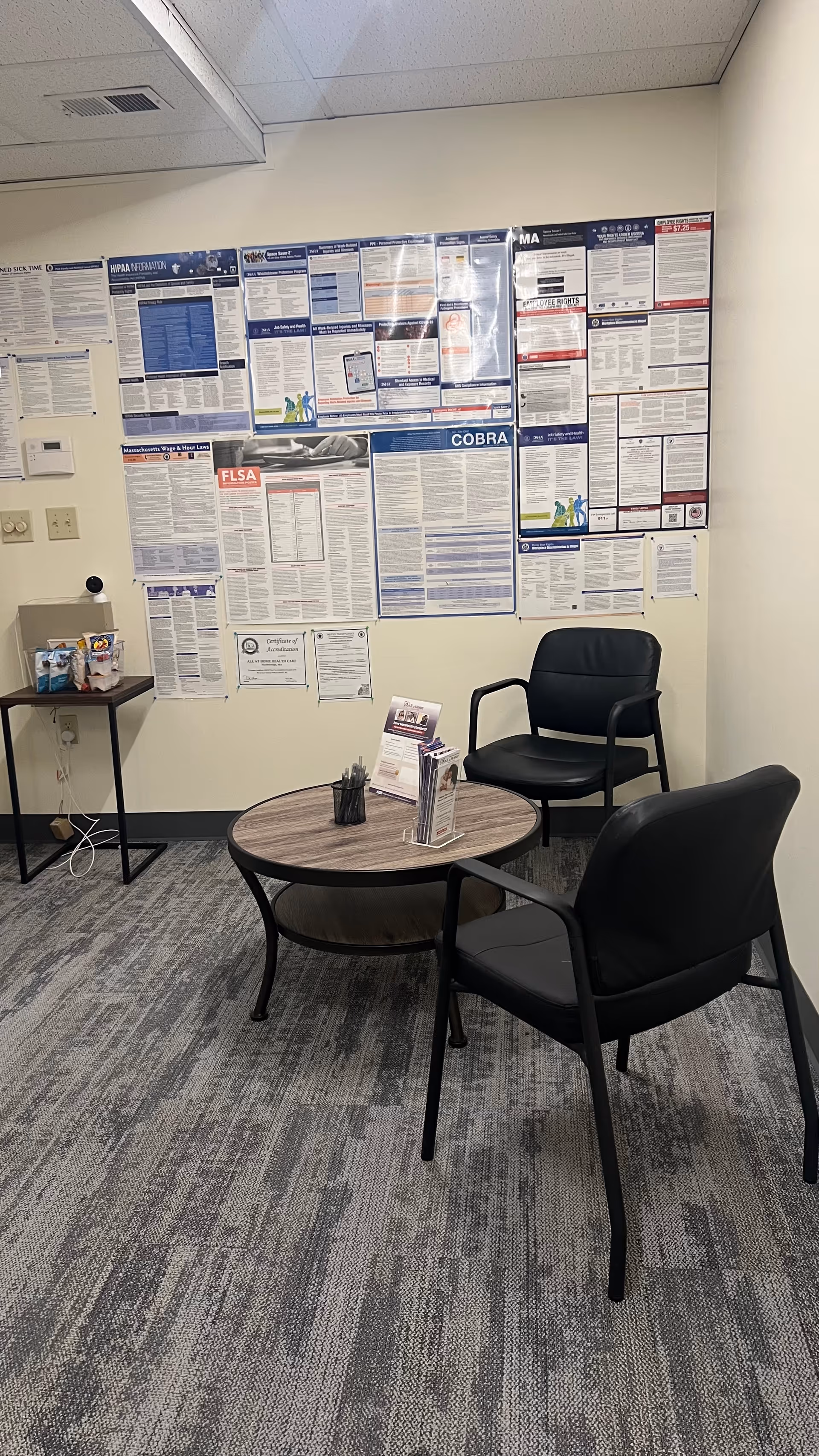 Waiting area with posters on the wall and two black chairs.