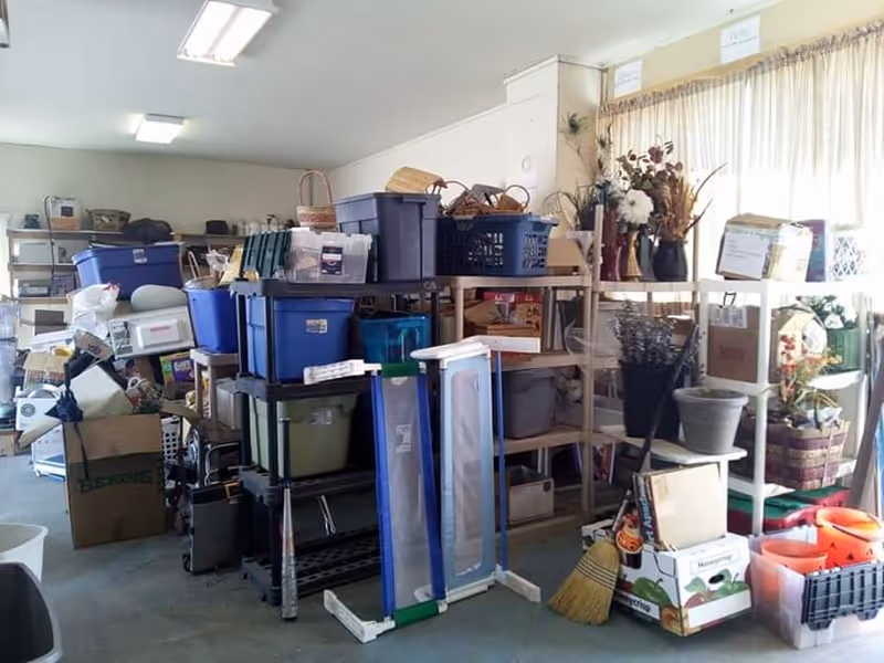 Interior storage room cluttered with shelves, baskets, bins, and stacked boxes.