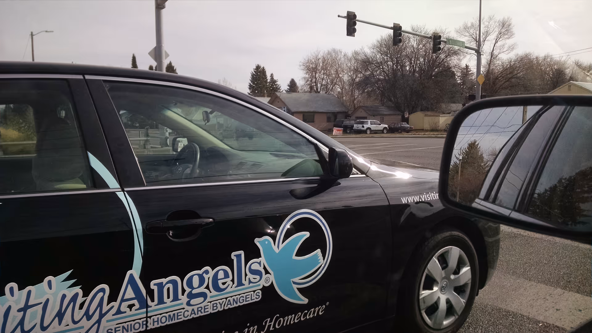 A Visiting Angels home care van parked at a street intersection with the logo visible.