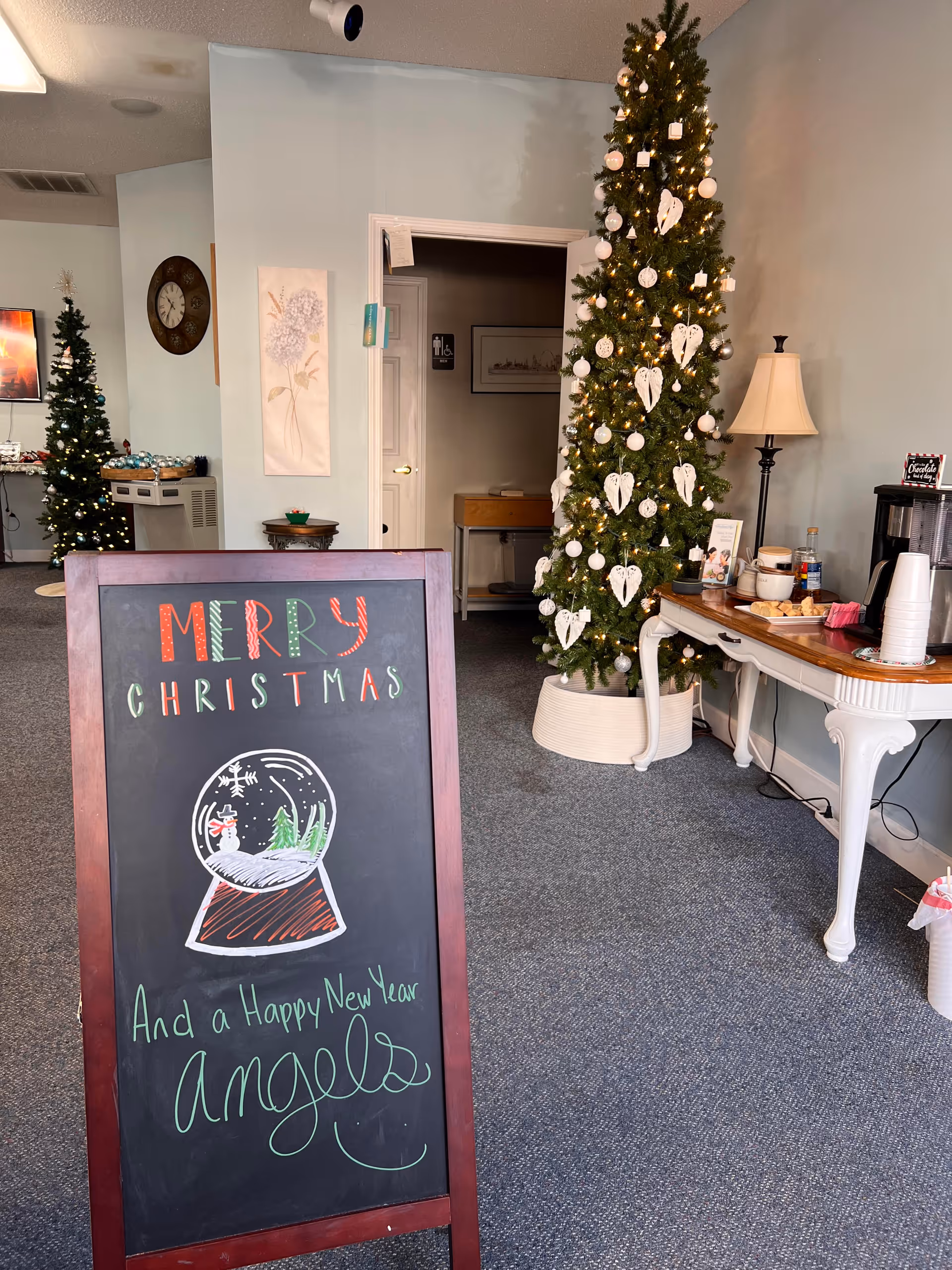 Lobby area with a tall Christmas tree, chalkboard sign, and refreshment table.