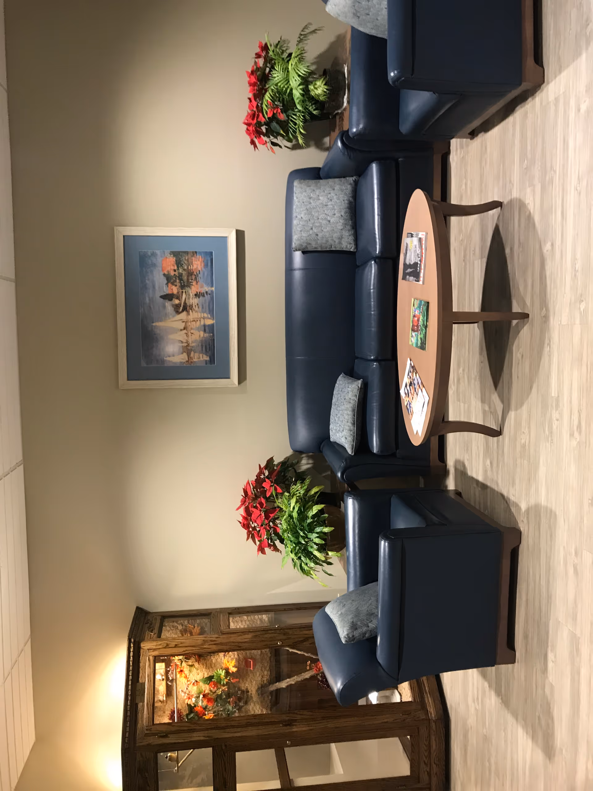 Indoor lounge with blue leather sofas, a round coffee table, and leafy plants.