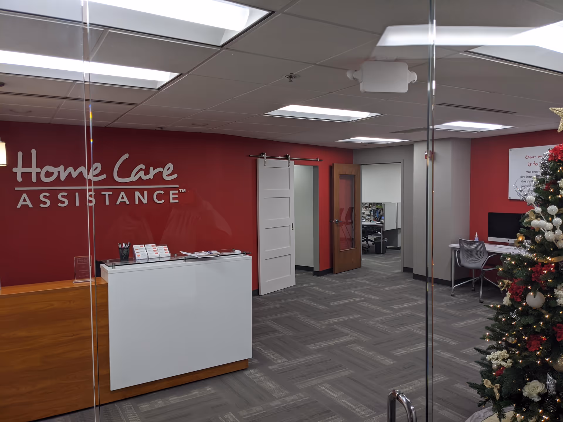 Reception area of Home Care Assistance facility featuring a red wall and Christmas tree.