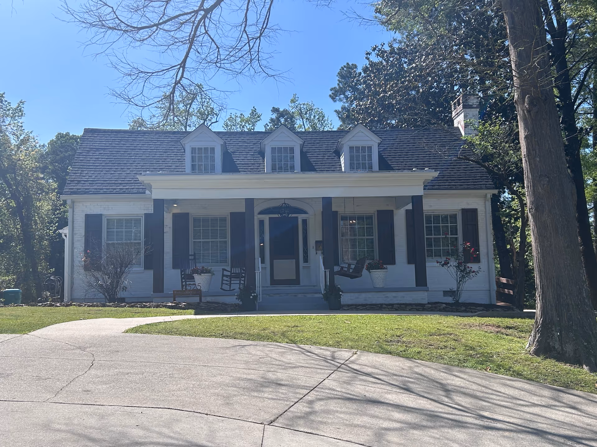 White cottage-style senior living building with a porch and rocking chairs.
