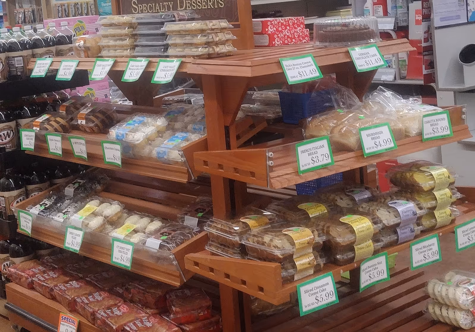 Wooden bakery display with breads, pastries, and price tags inside a shop.
