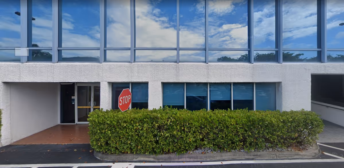 Exterior view of a Senior Helpers facility with glass windows, hedge, and a stop sign.