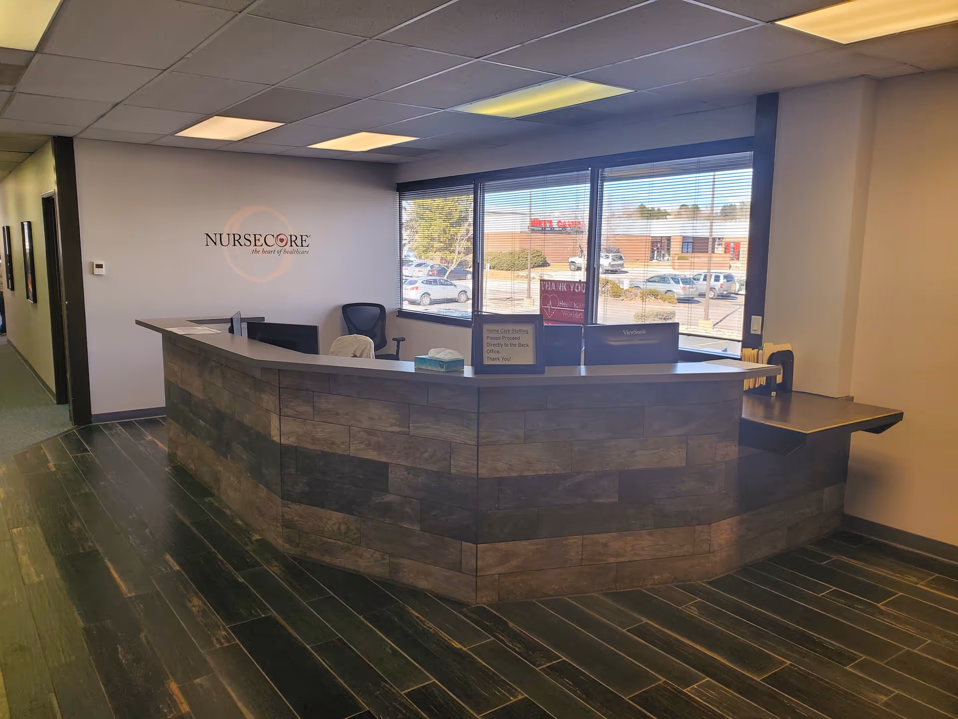 Curved stone-front reception desk in a bright NurseCore facility lobby.