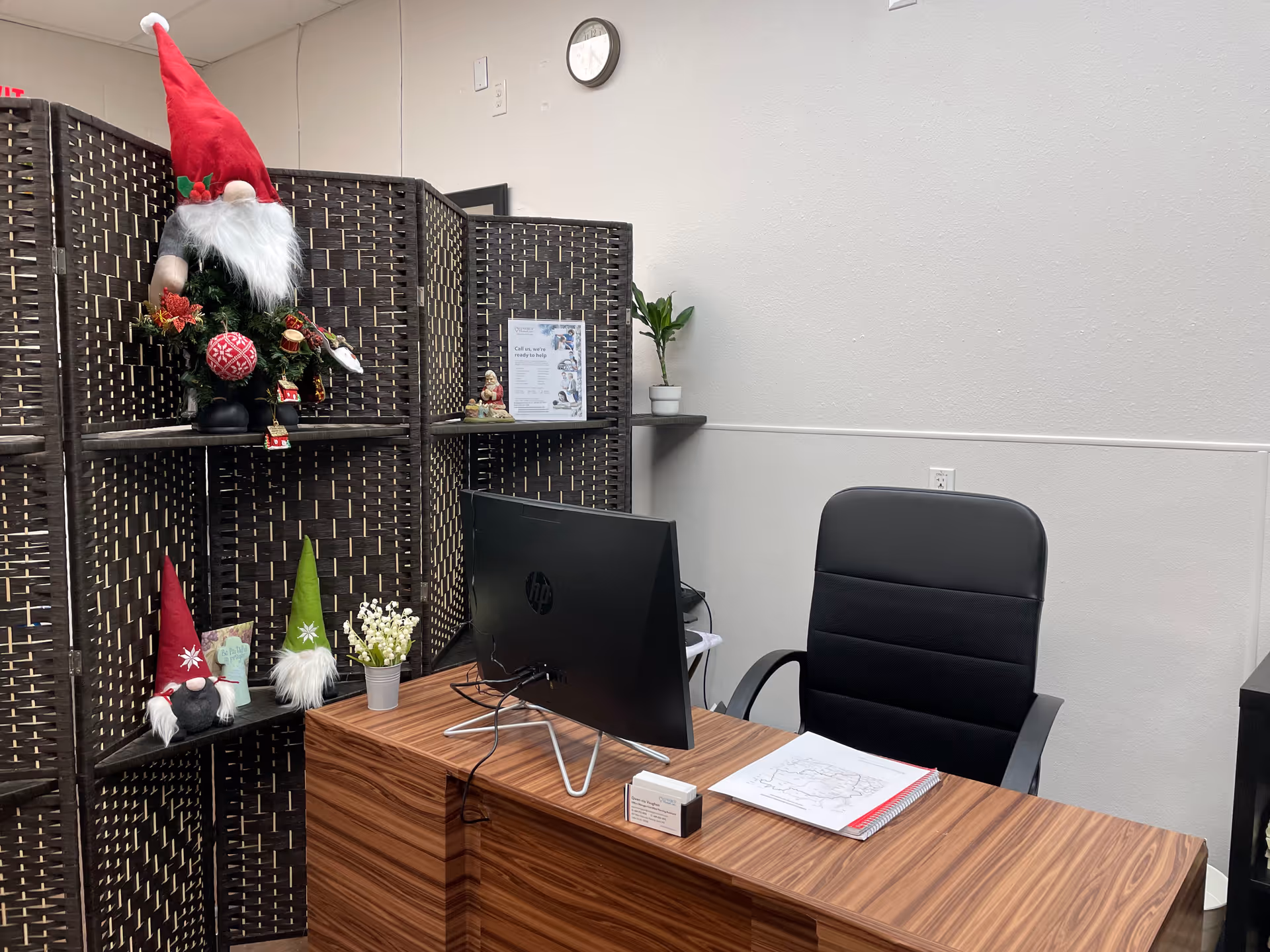 Office desk with computer monitor, chair, and holiday decorations in a partitioned indoor room.