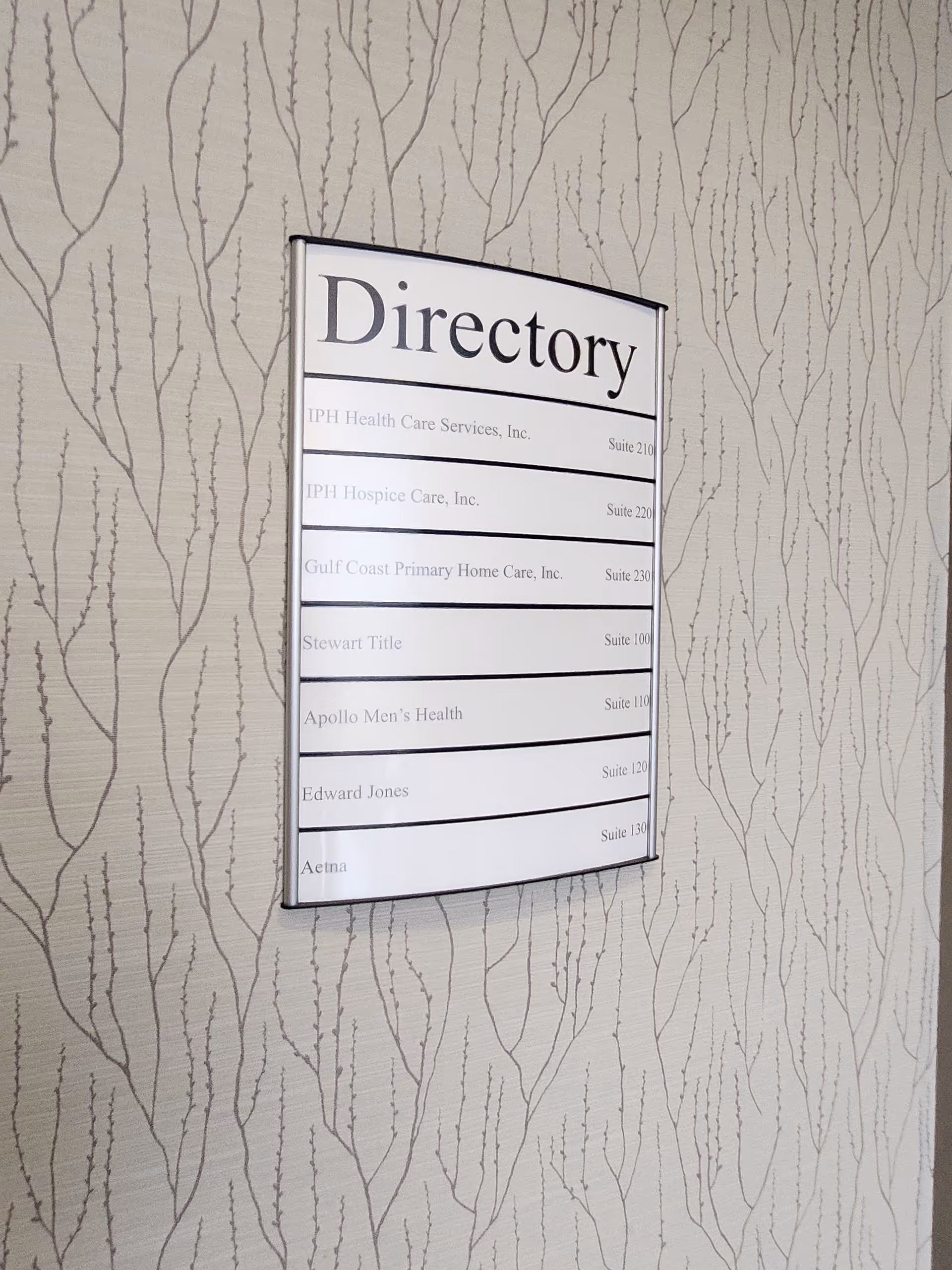 A wall-mounted directory sign listing suites, set against patterned wallpaper in a senior living facility.