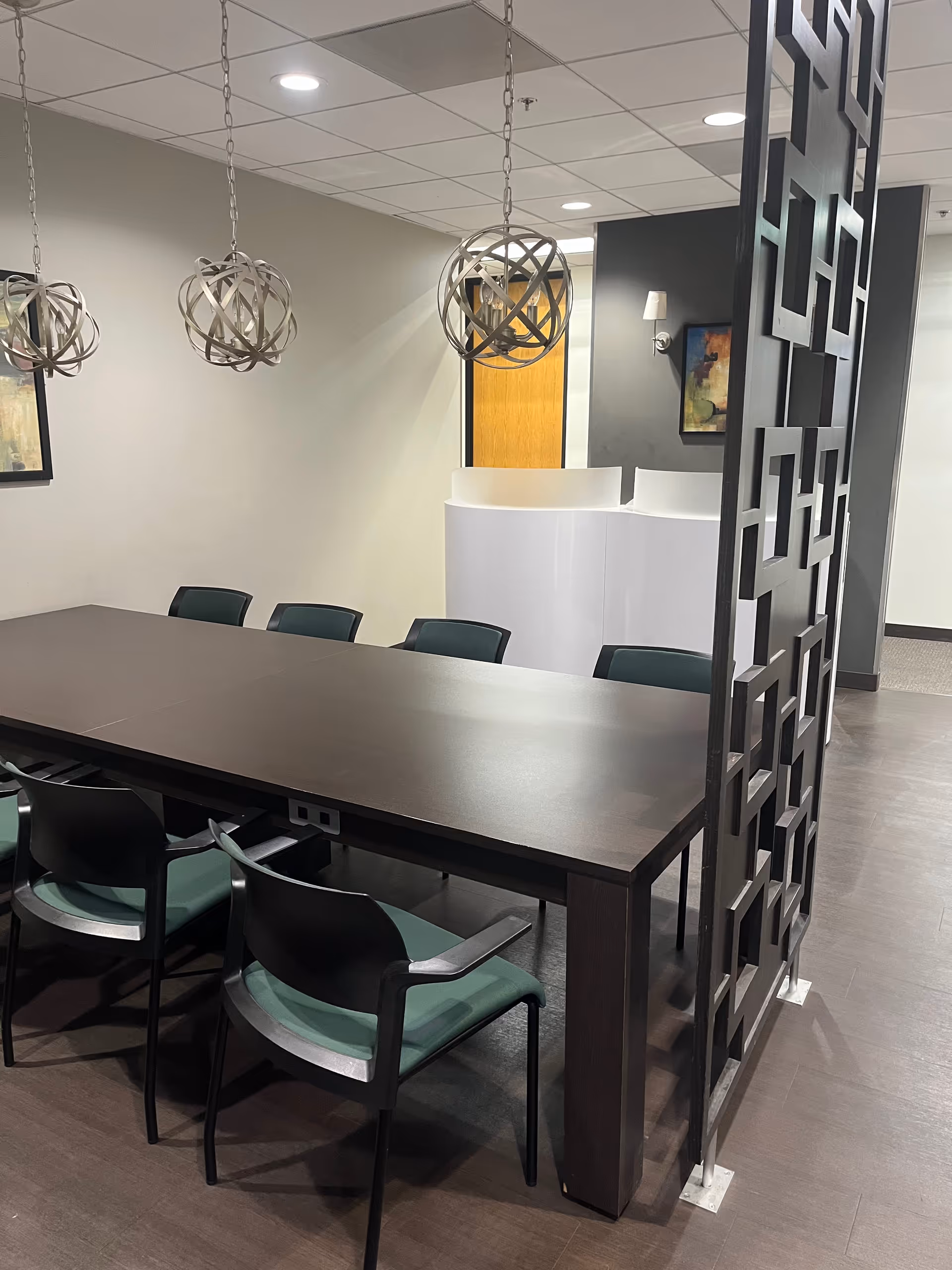 A long dark dining table with teal chairs in a modern senior living dining area.