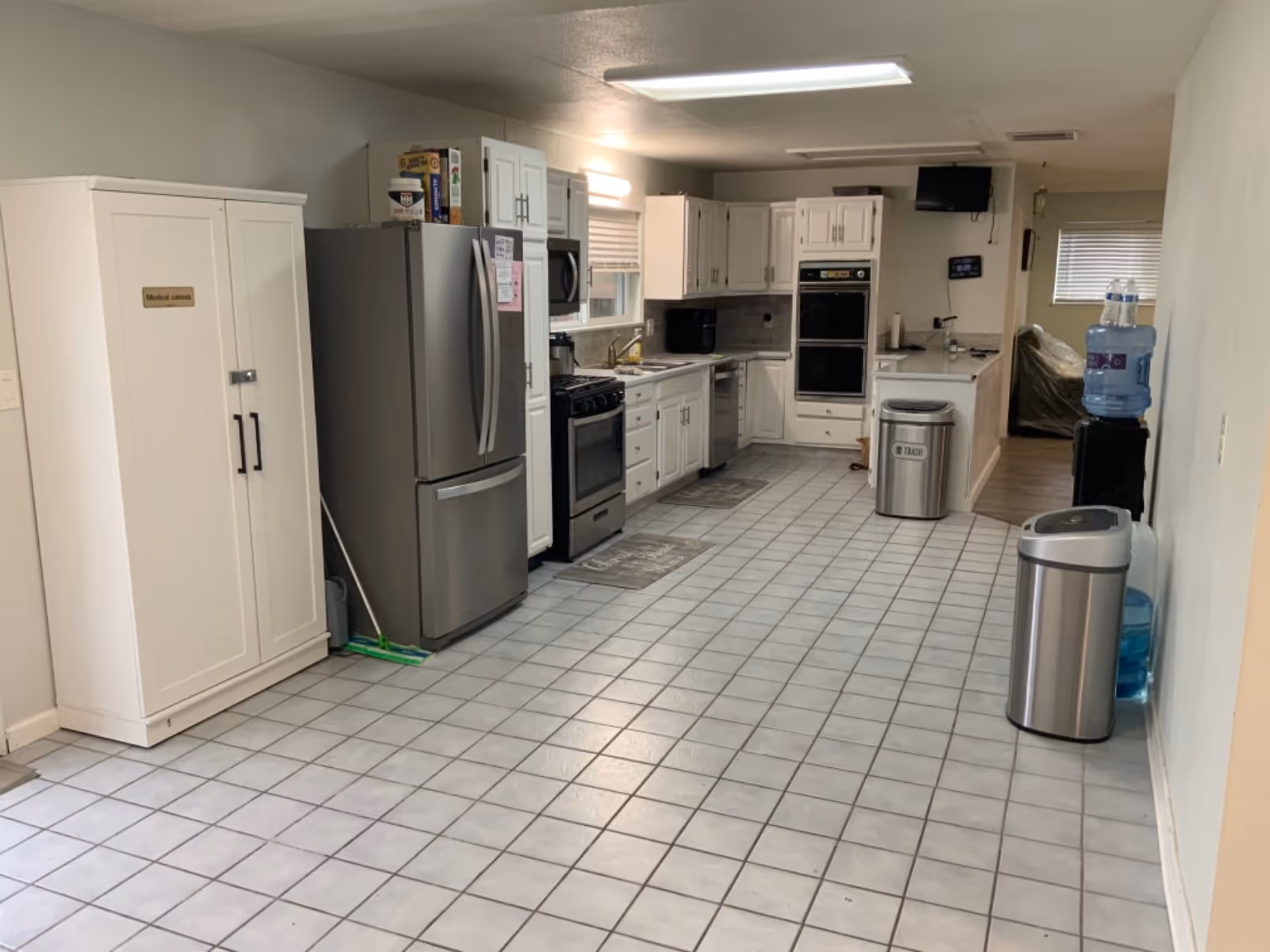 Interior senior living facility kitchen with stainless steel appliances and white cabinets.
