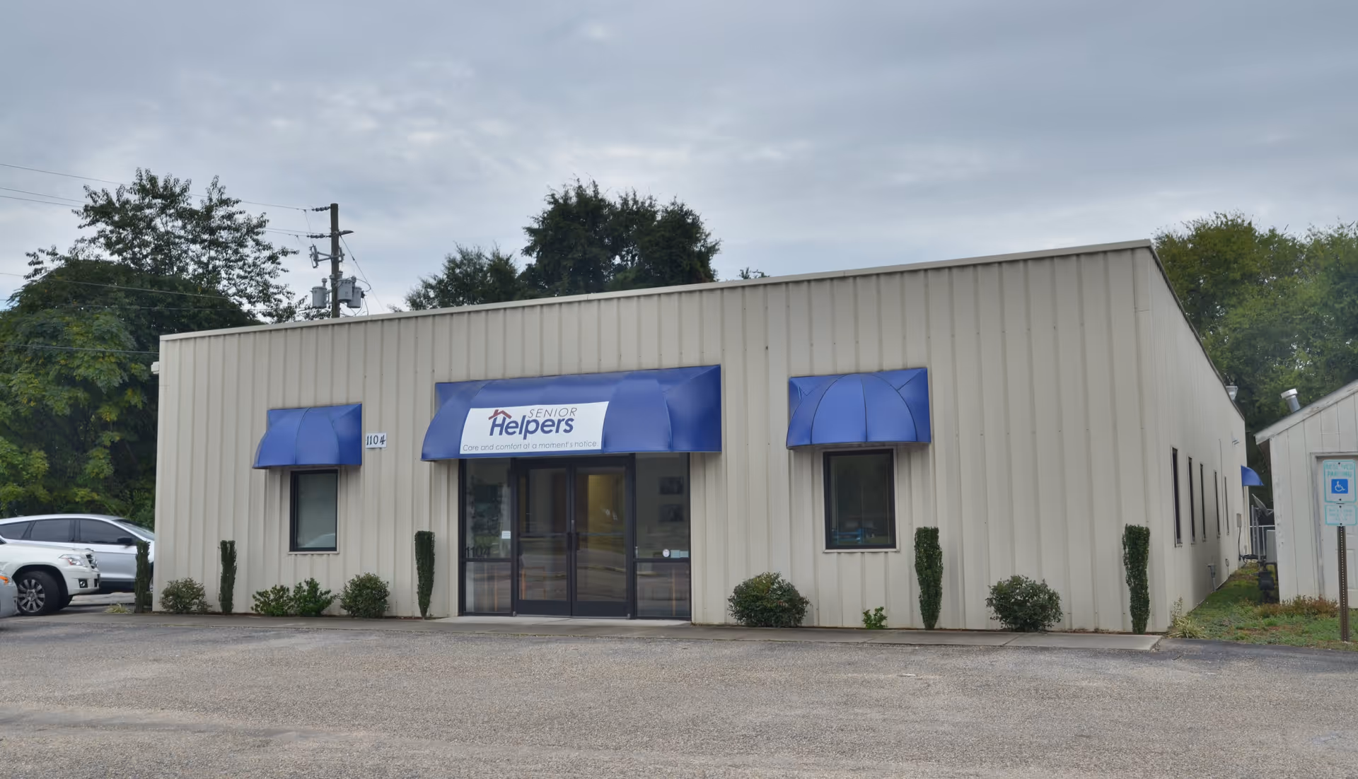 Exterior view of a Senior Helpers facility with blue awnings and a glass entrance.