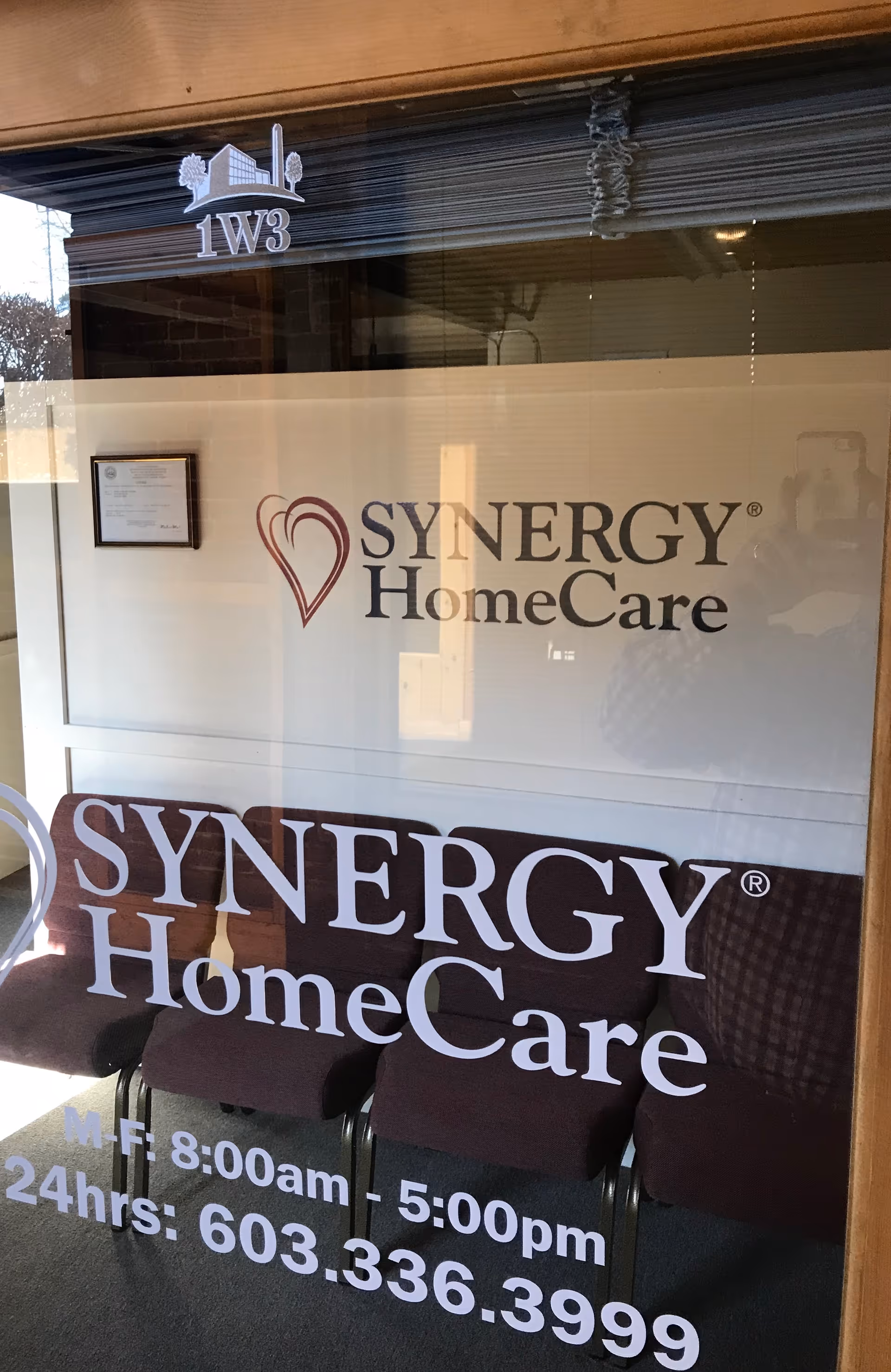 Glass storefront displays SYNERGY HomeCare logo with purple chairs visible inside.