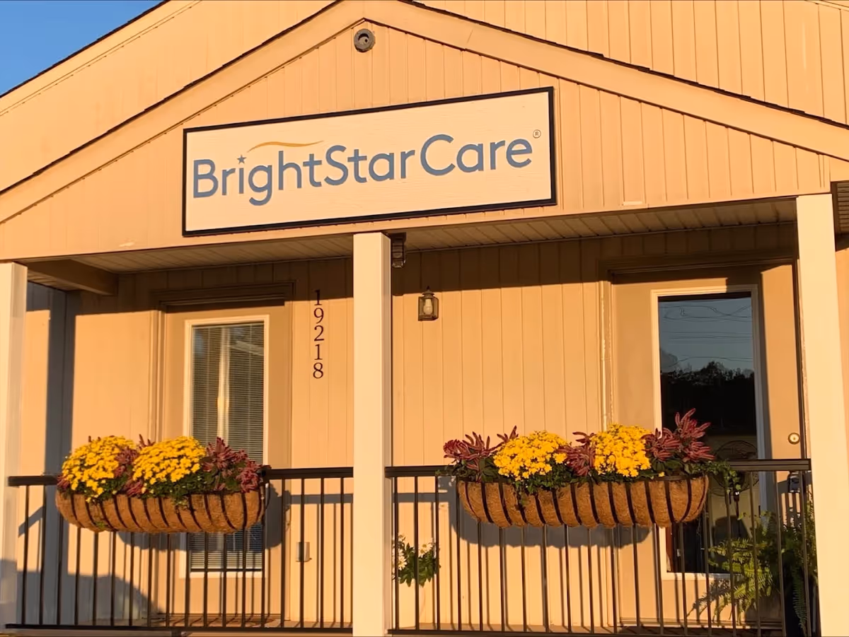 Front of BrightStarCare facility with sign, beige siding, and flower-filled planters.