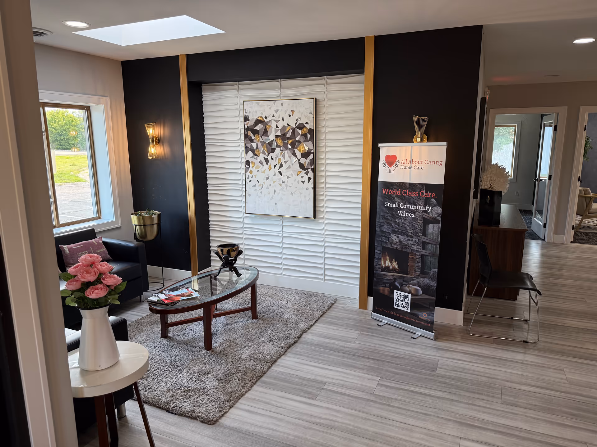 Modern lobby with seating, glass coffee table, wall art, and an All About Caring banner.
