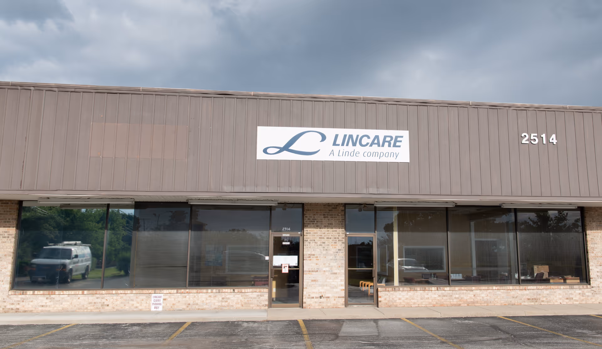 Front view of LINCARE building with sign, brick facade, large windows, and parking lot.