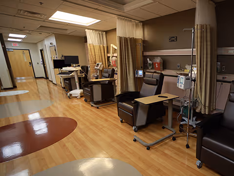 Interior of medical treatment area with partition curtains, reclining chairs, IV stands, and monitors.