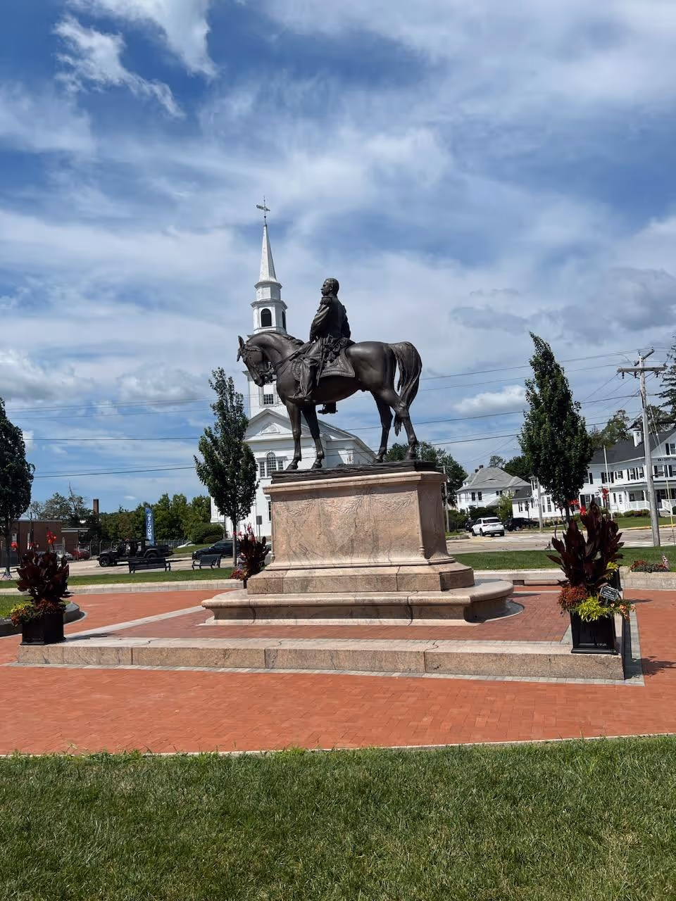 Bronze equestrian statue on a stone pedestal amid a brick plaza with planters.