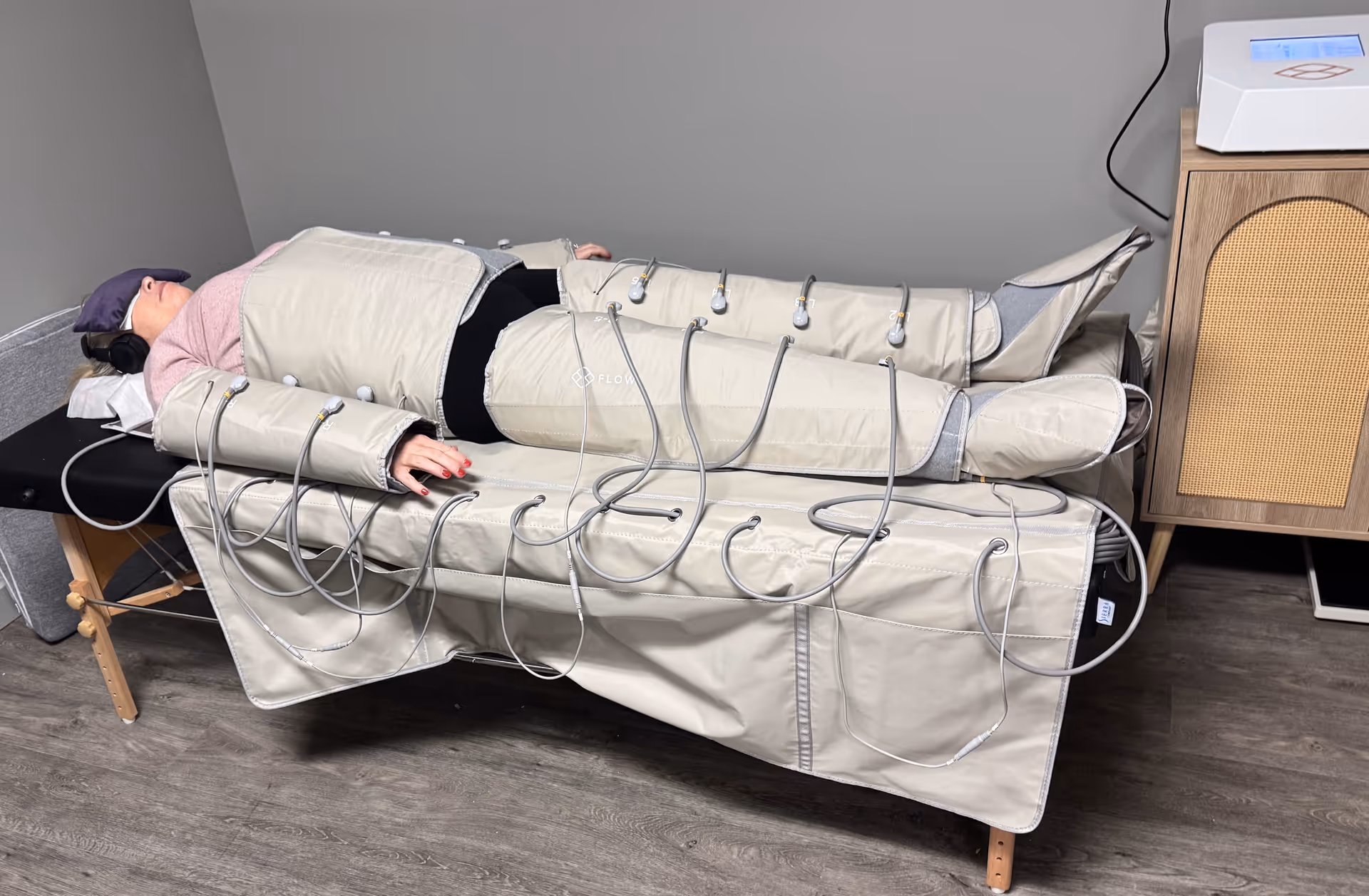 Person lies on a padded therapy table with cables in a treatment room.