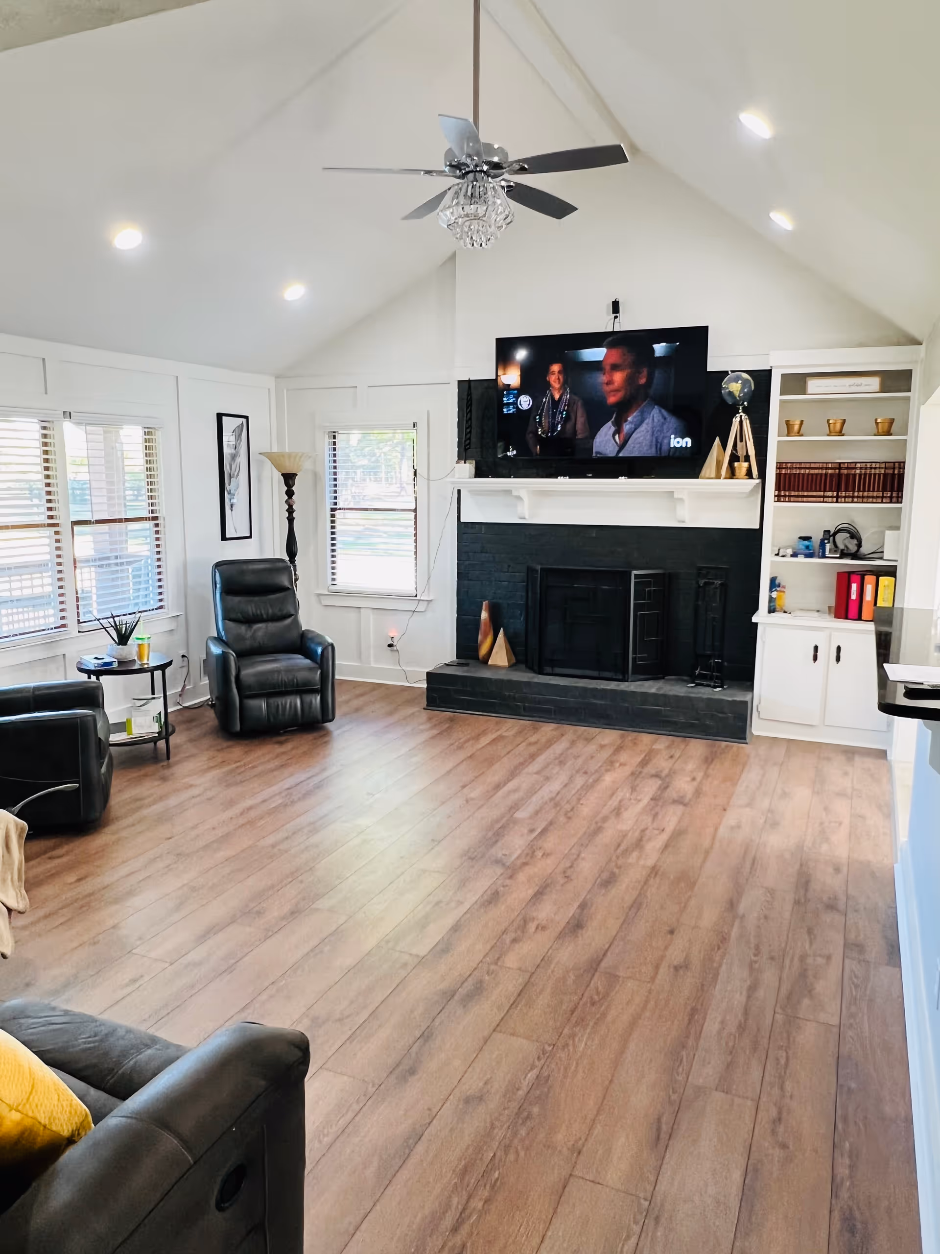 Bright living room with leather seating, fireplace, built-in shelves, and a wall-mounted TV.