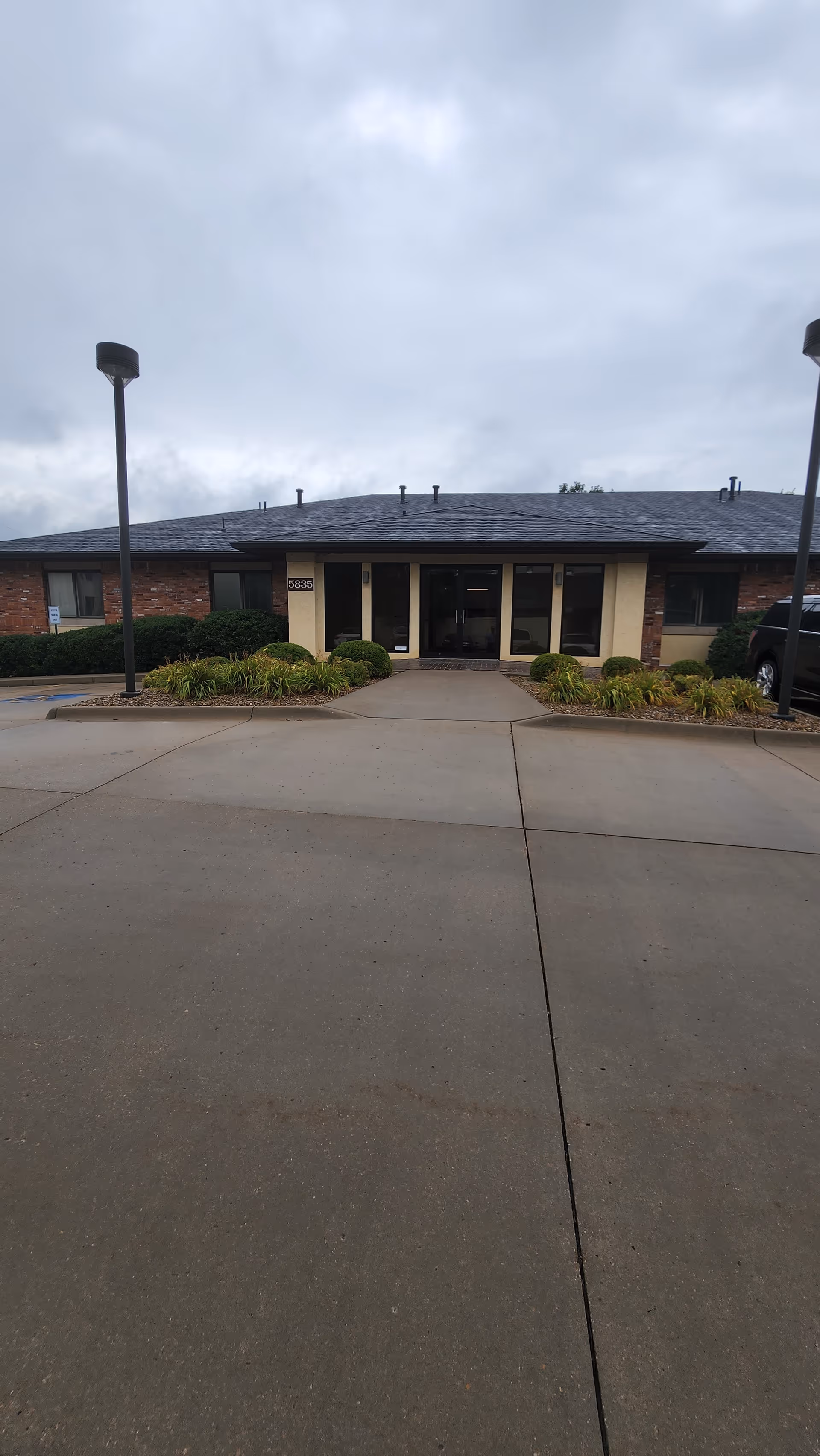 Exterior view of a single-story brick building with glass entrance and landscaping.