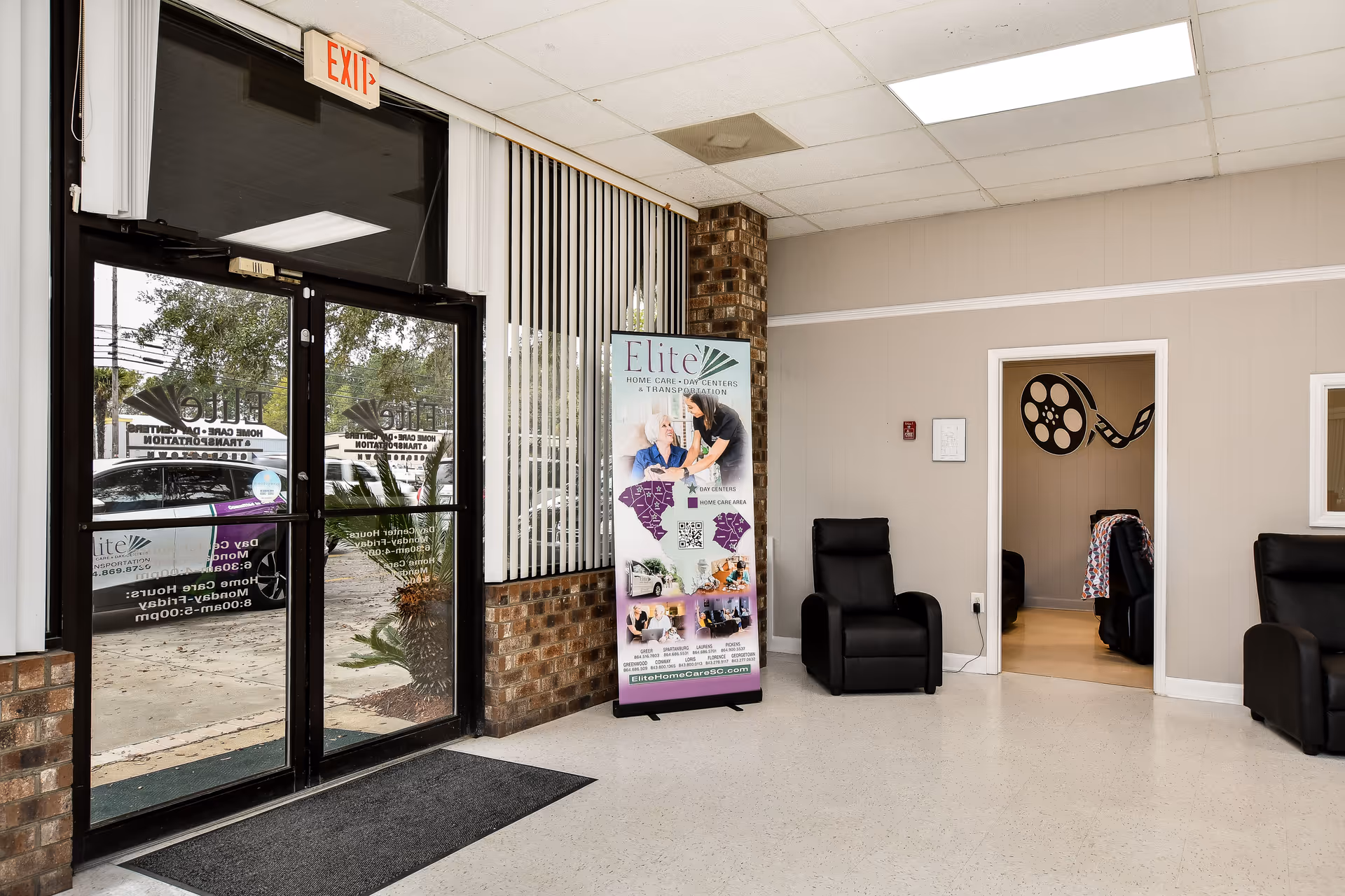 Lobby area with glass entrance doors, chairs, and an Elite Home Care and Day Centers banner.