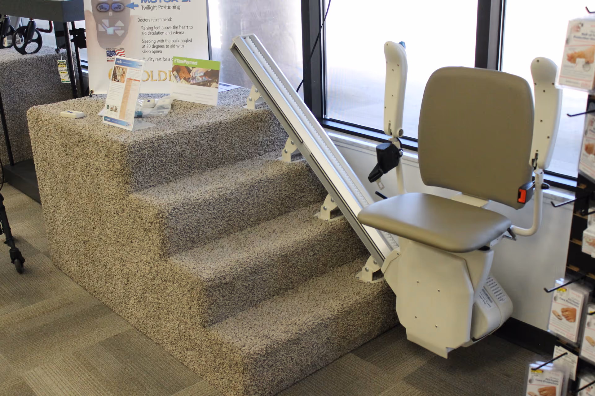A beige stair lift chair mounted beside carpeted steps inside a showroom.