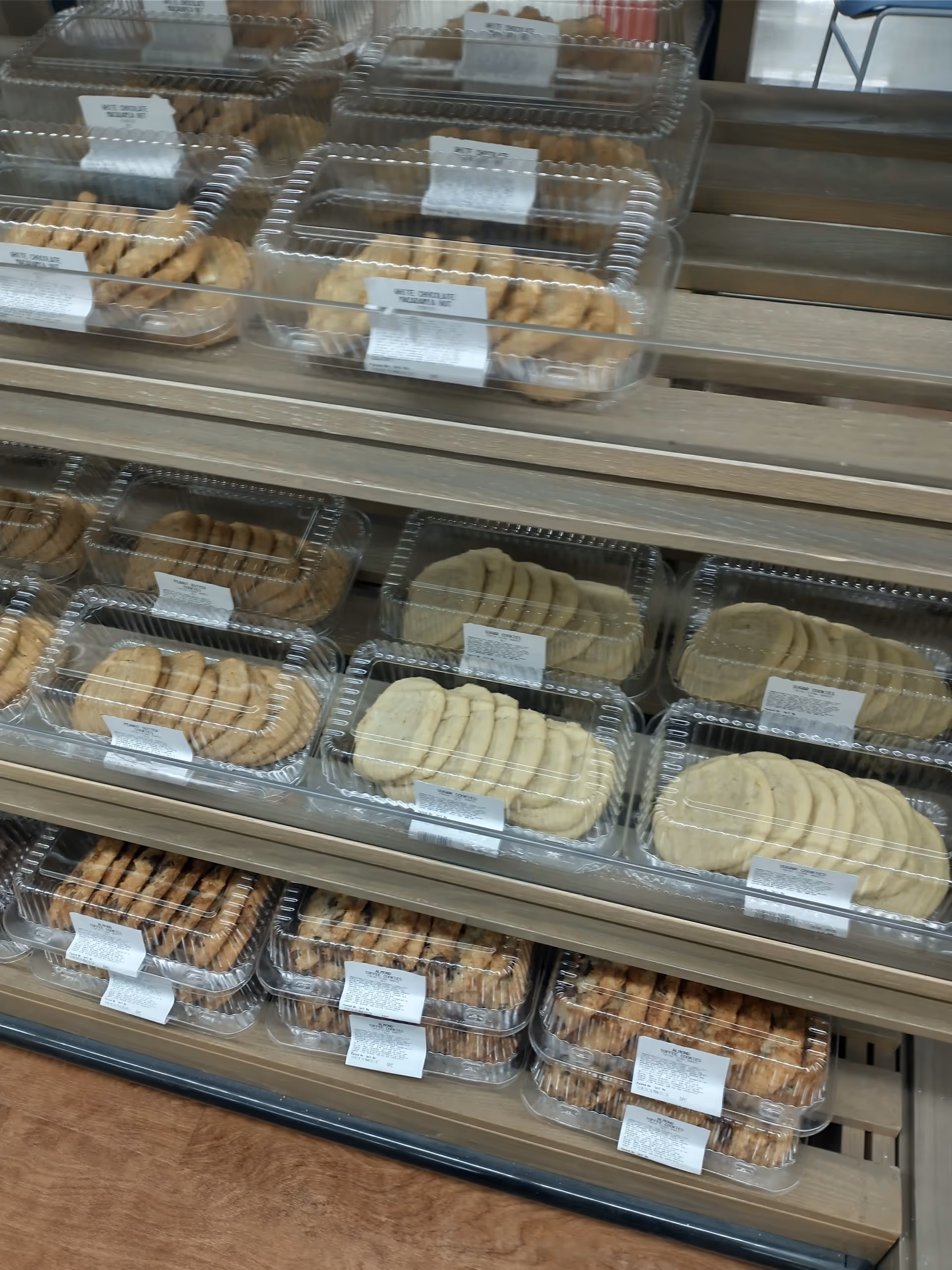 Shelves display clear plastic containers of assorted cookies in a drugstore.