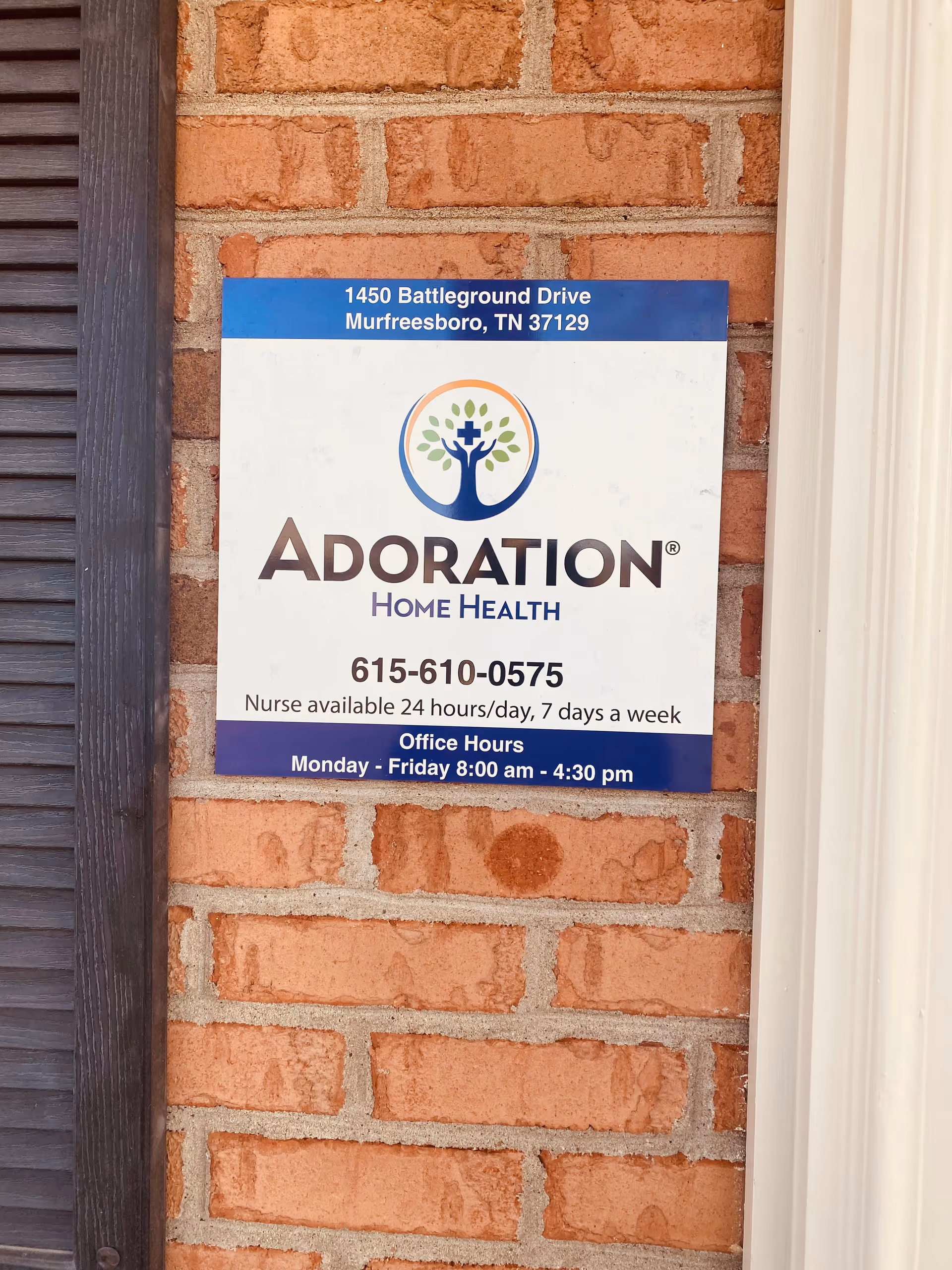 Adoration Home Health sign mounted on a brick exterior building front.