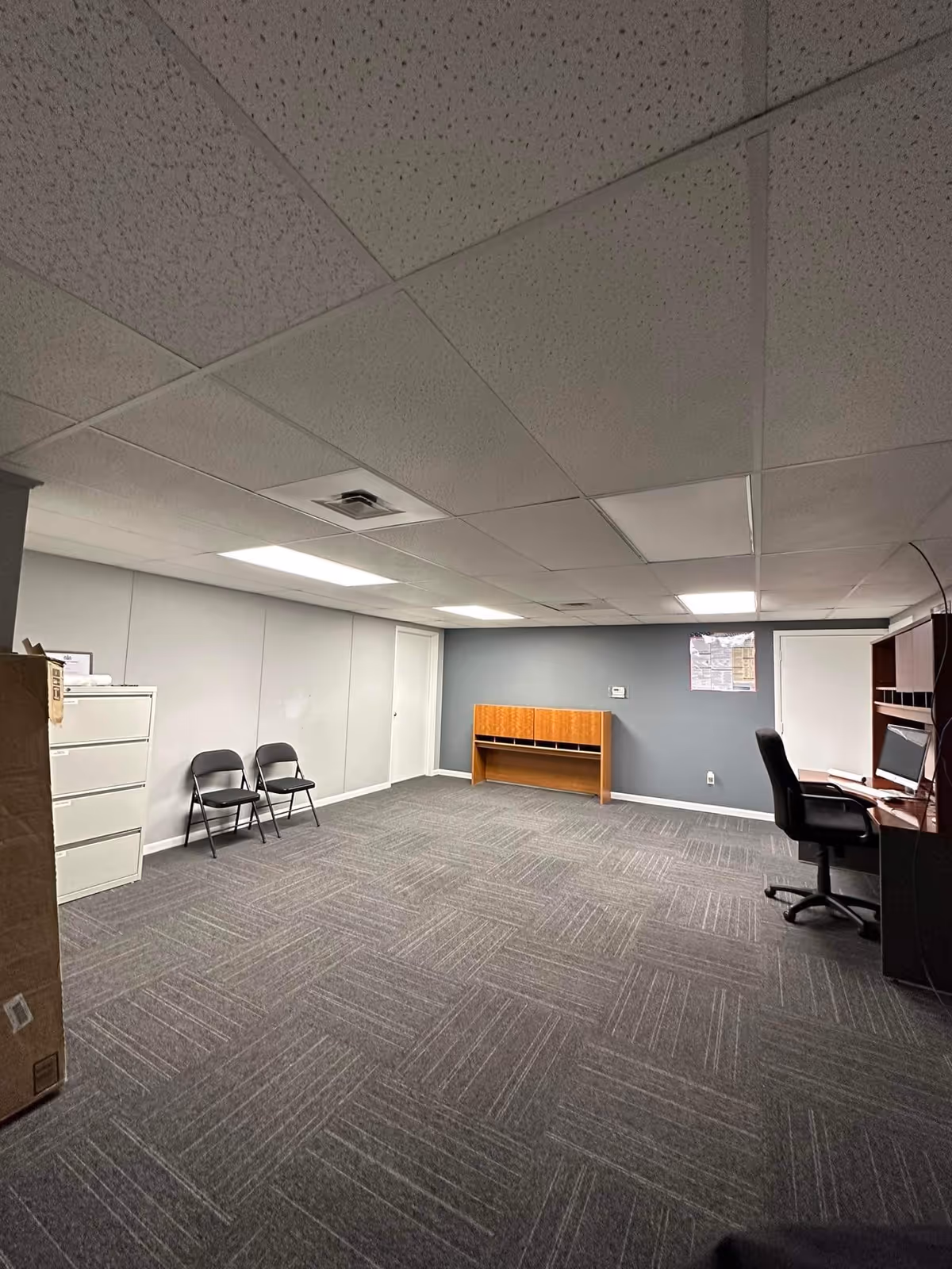 An empty office-like room in Everest Home Care LLC with desk, chairs, and filing cabinet.