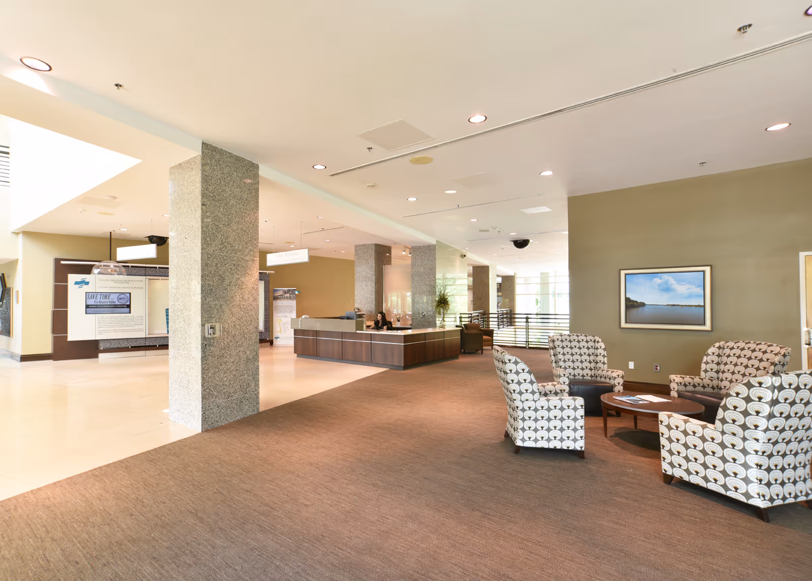 Bright lobby with a reception desk, pillars, and patterned seating.