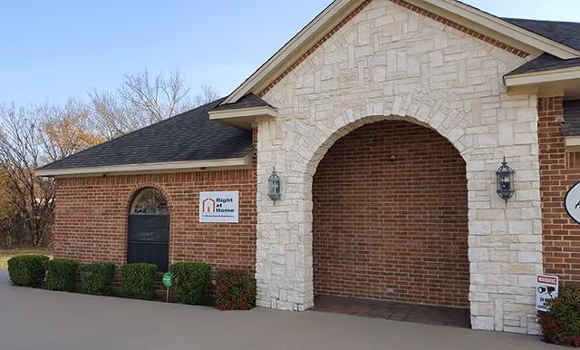 Exterior of Right at Home senior living facility featuring a brick facade and arched stone entrance.
