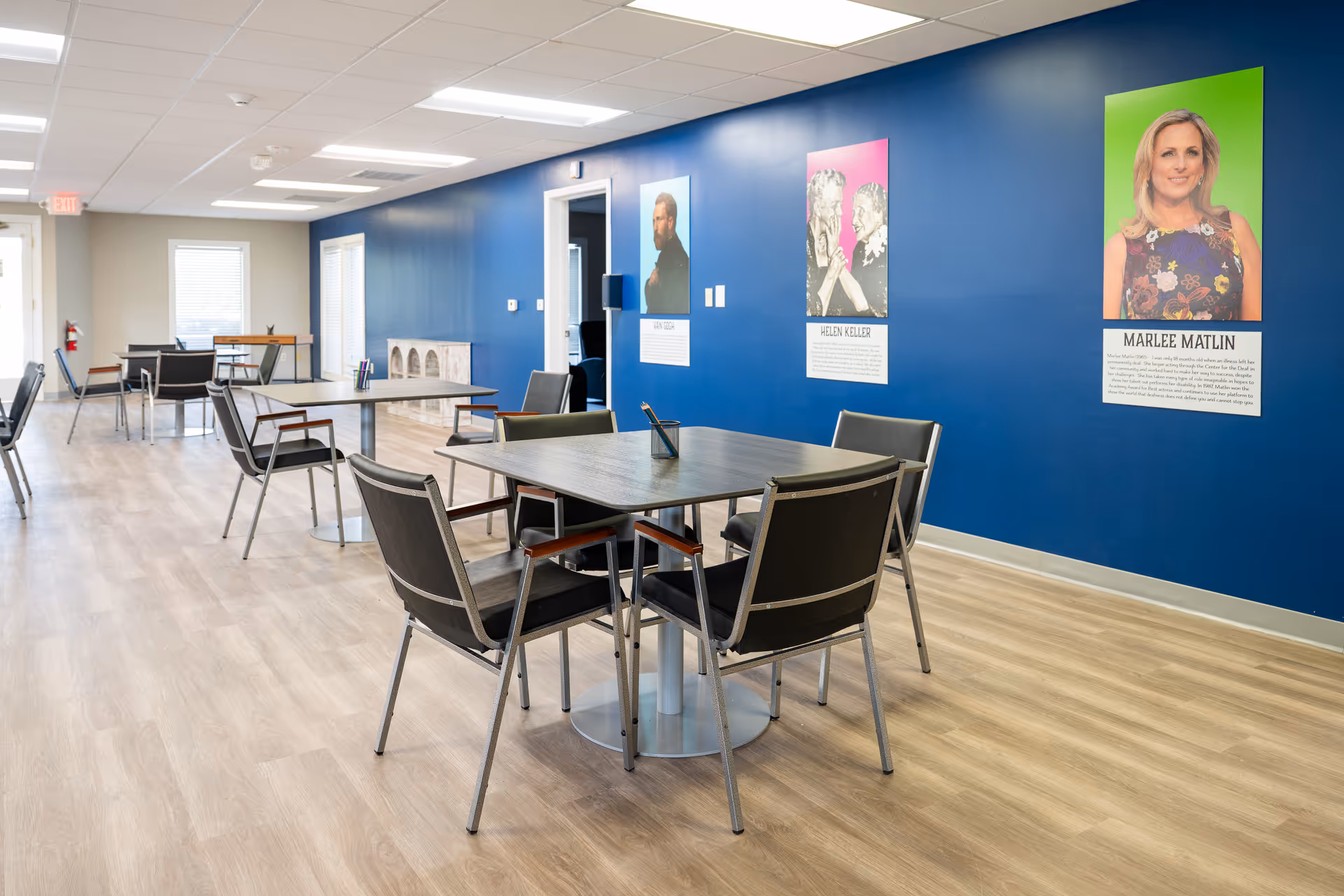 A bright dining area with blue wall, posters, and several tables and chairs.