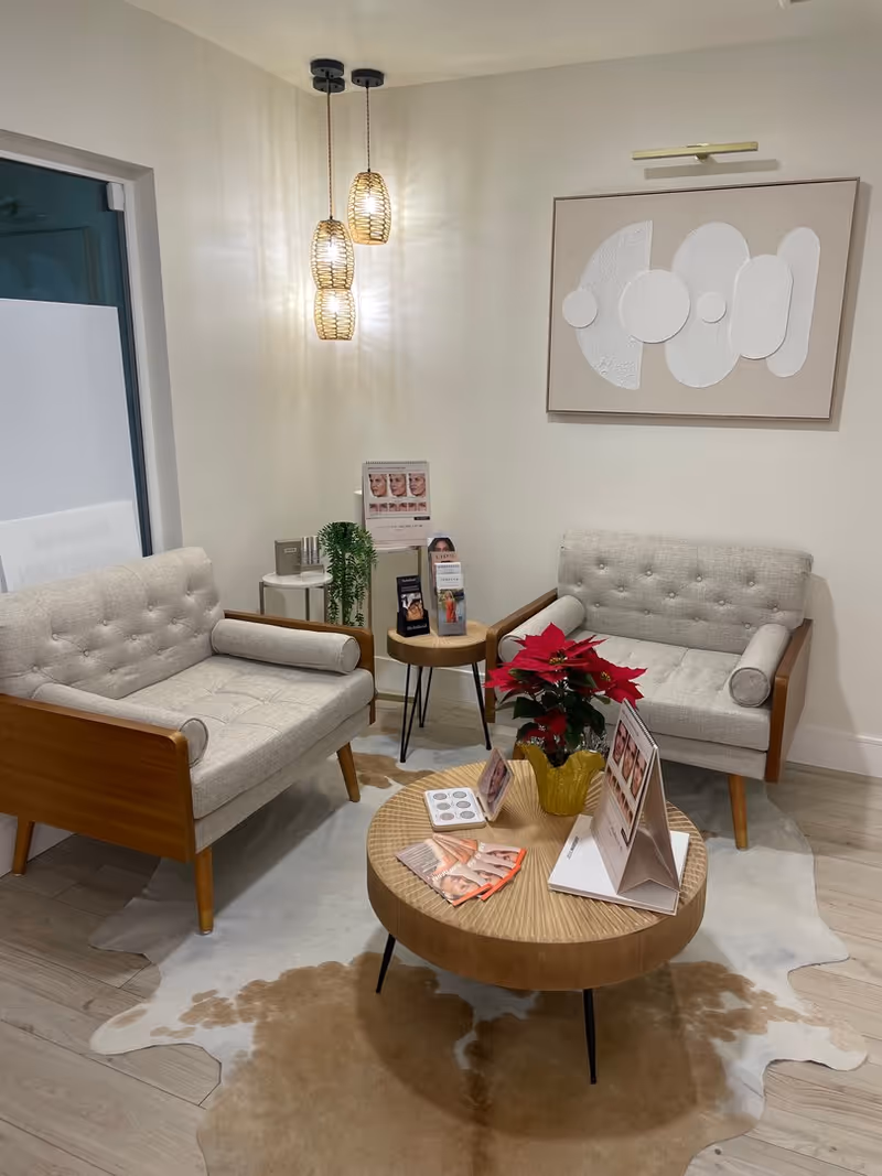 Modern waiting lounge with two tufted sofas, round coffee table, and hanging pendant lights.