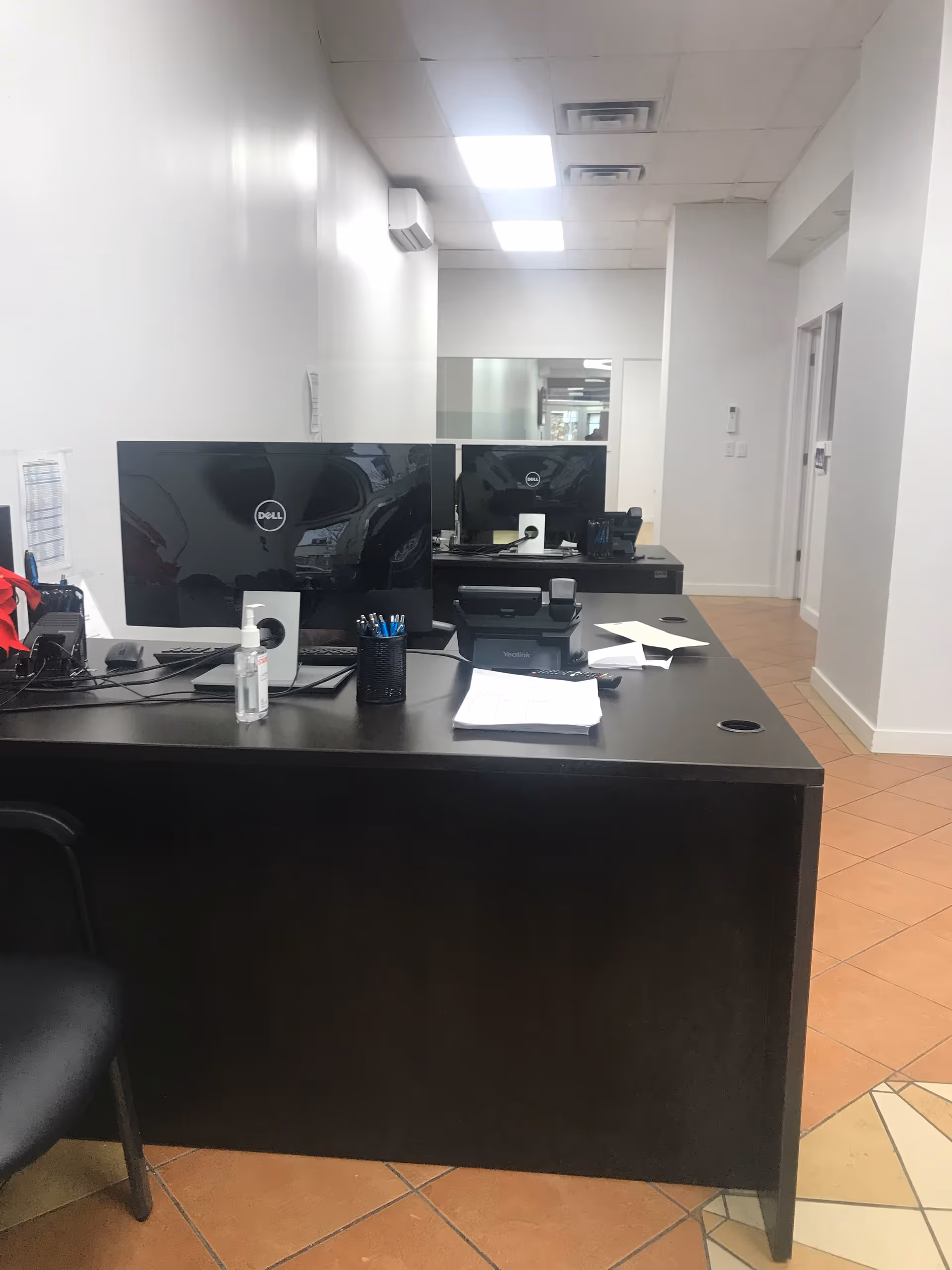 Interior office reception with monitors, desk supplies, and papers.