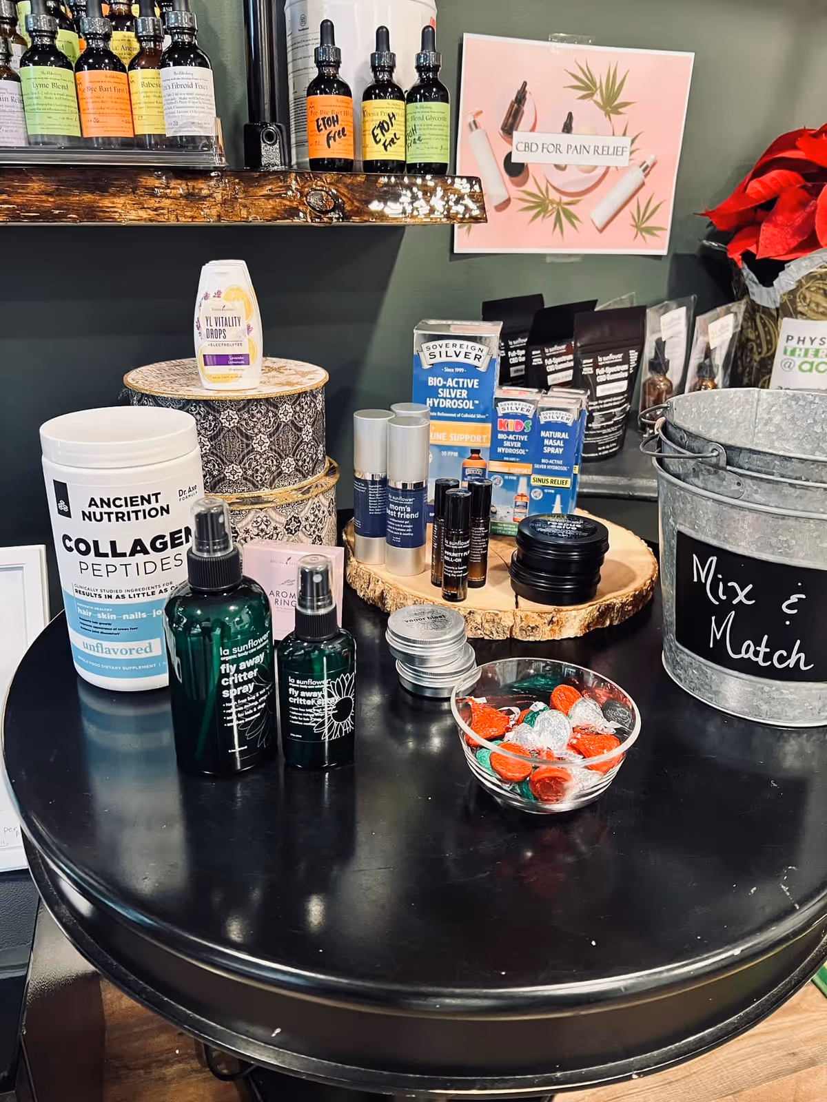 Round black table displaying wellness bottles, skincare products, and a bowl of candies