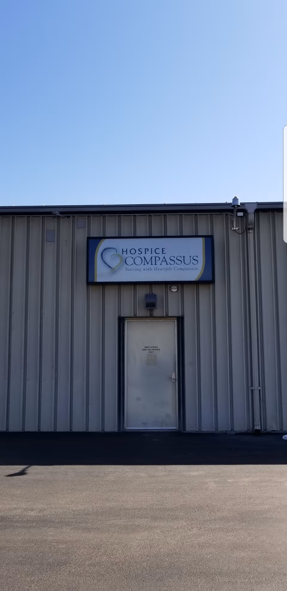 Exterior view of a gray metal building with Hospice Compassus sign and door.
