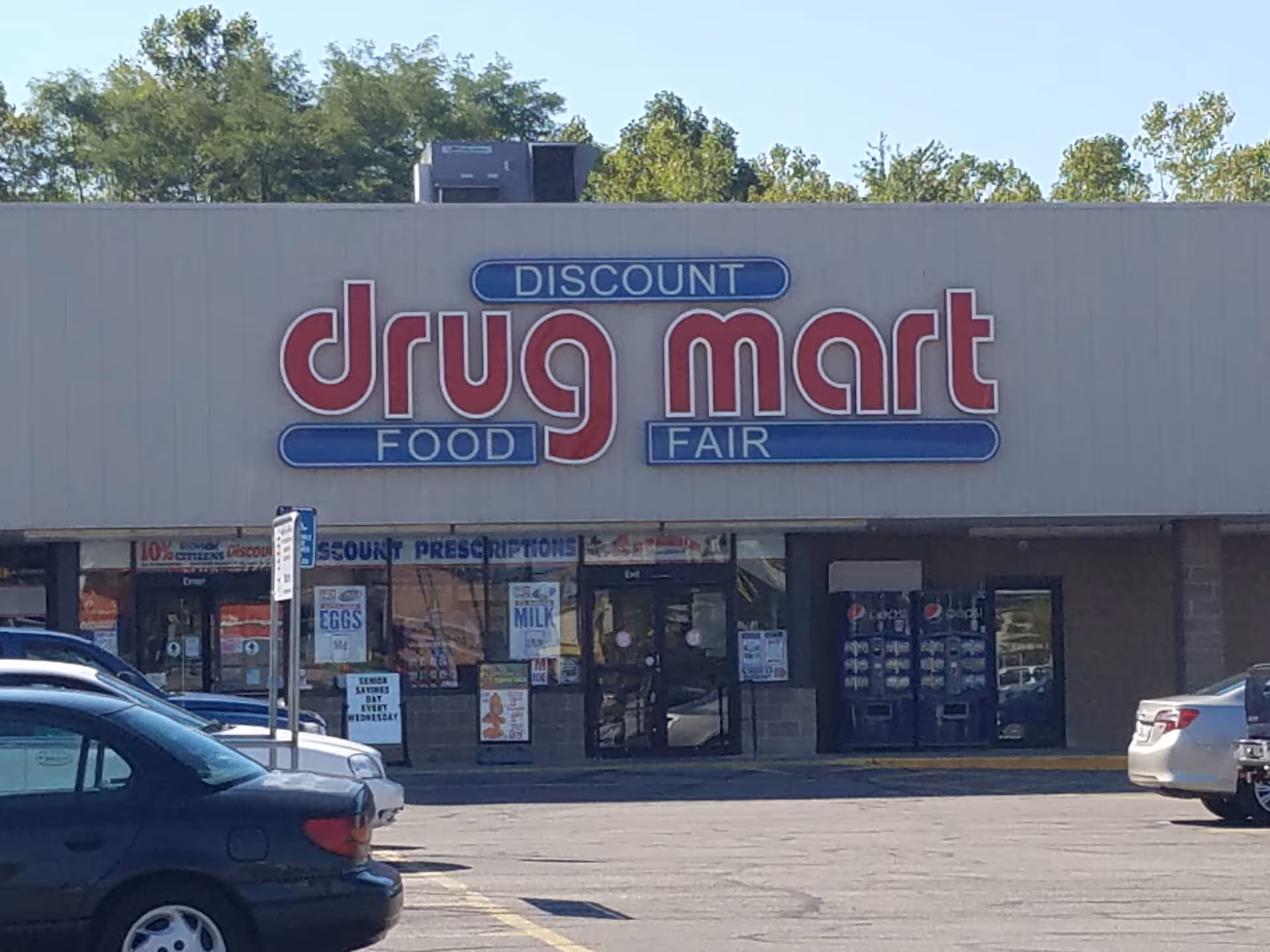 Discount Drug Mart storefront with large sign and cars in the parking lot.