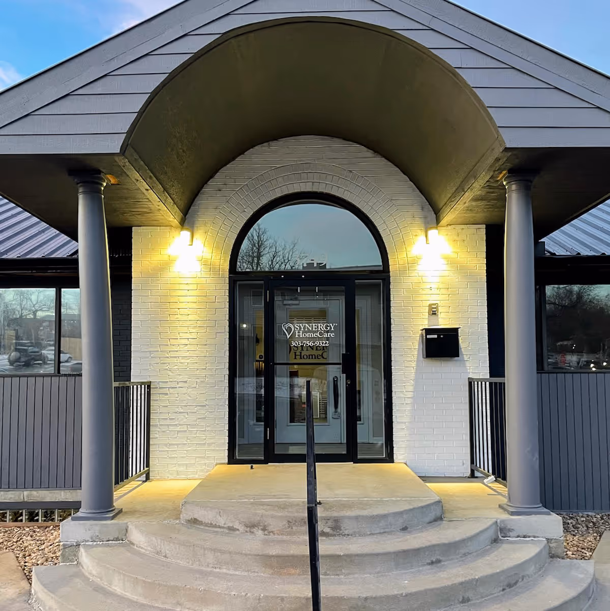 Front entrance of a Synergy HomeCare building with arched doorway and steps.