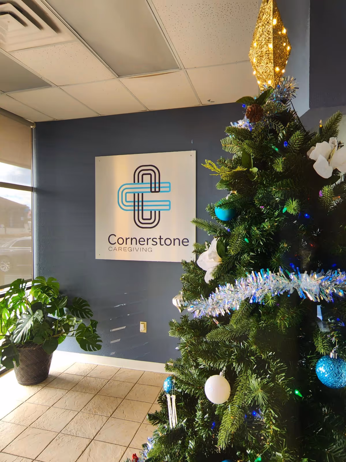 Indoor lobby area with a Cornerstone Caregiving sign and a decorated Christmas tree.