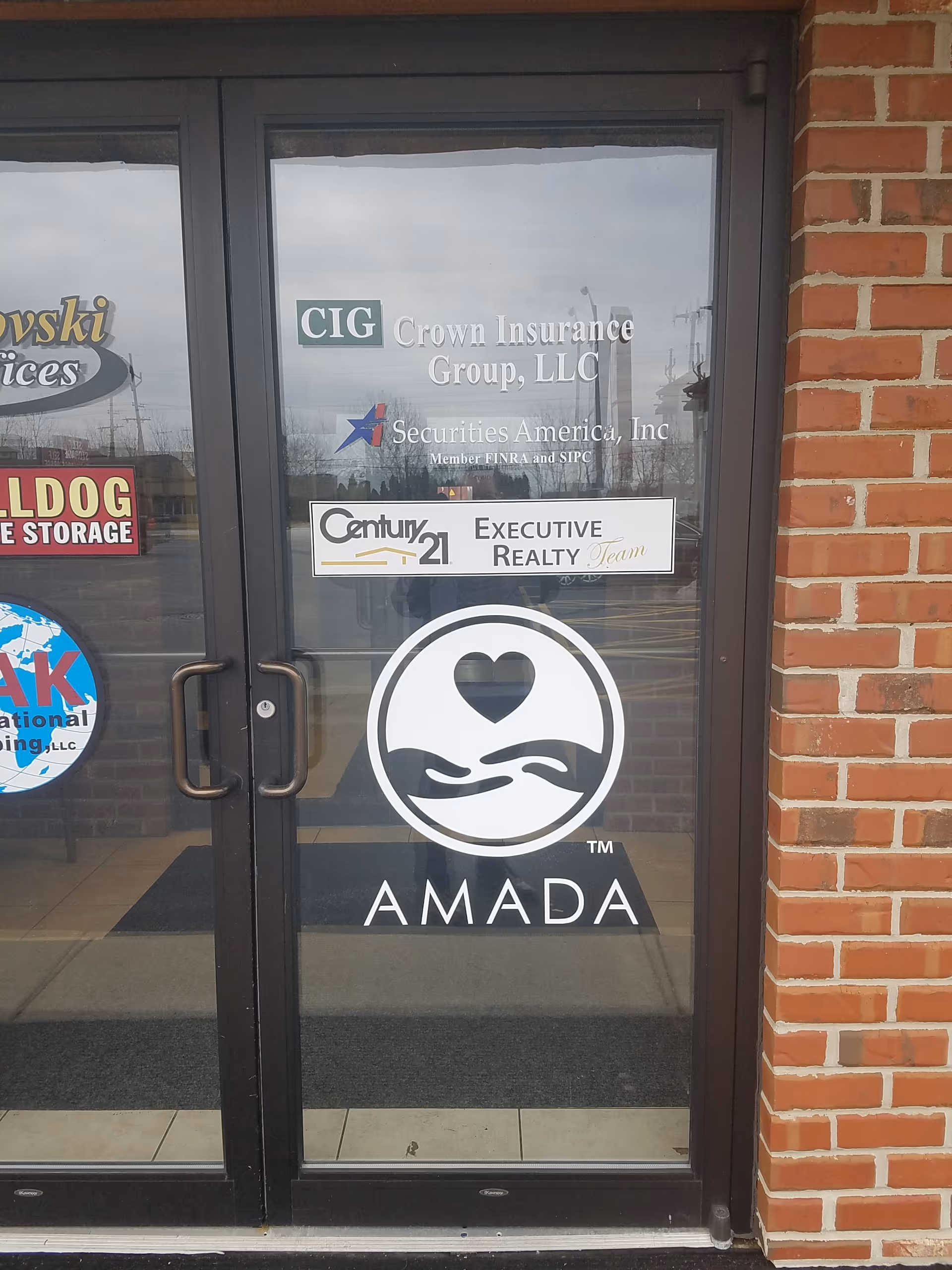 Glass doors display Amada logo and several business decals.
