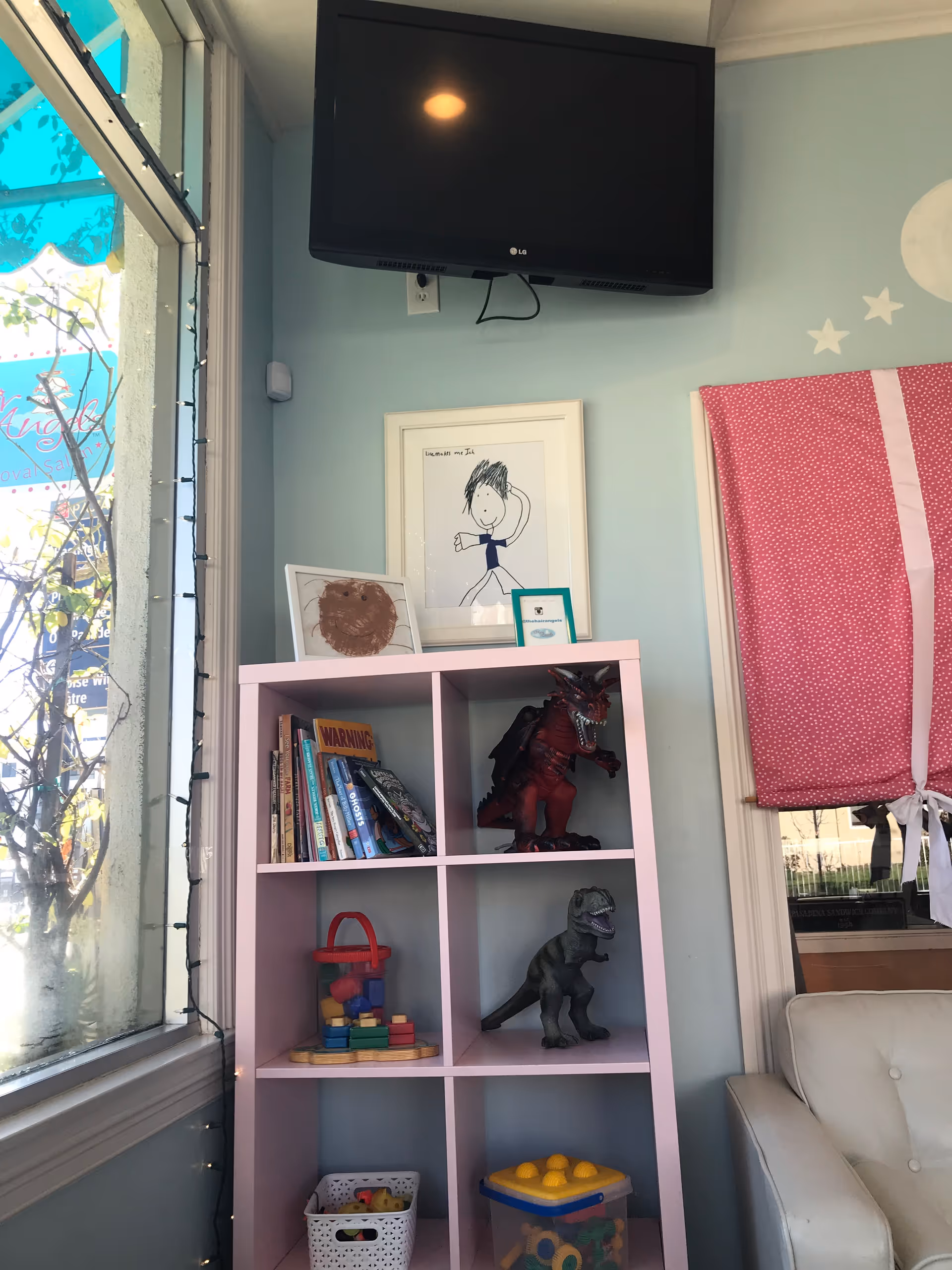 Pastel pink cubby shelves with toys and dinosaur figures in a light blue playroom.