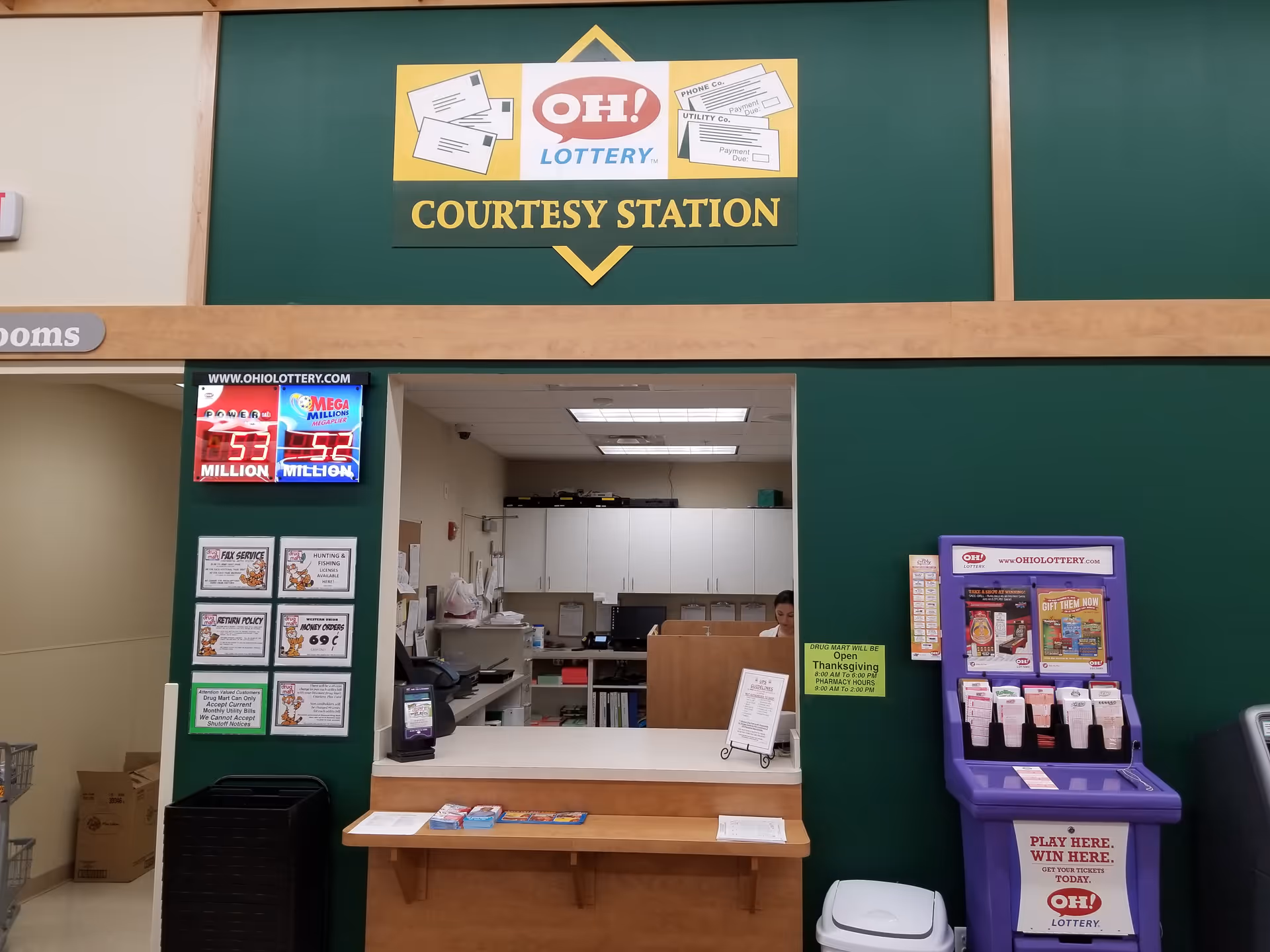 Interior view of a Discount Drug Mart counter labeled Courtesy Station with a staff member.