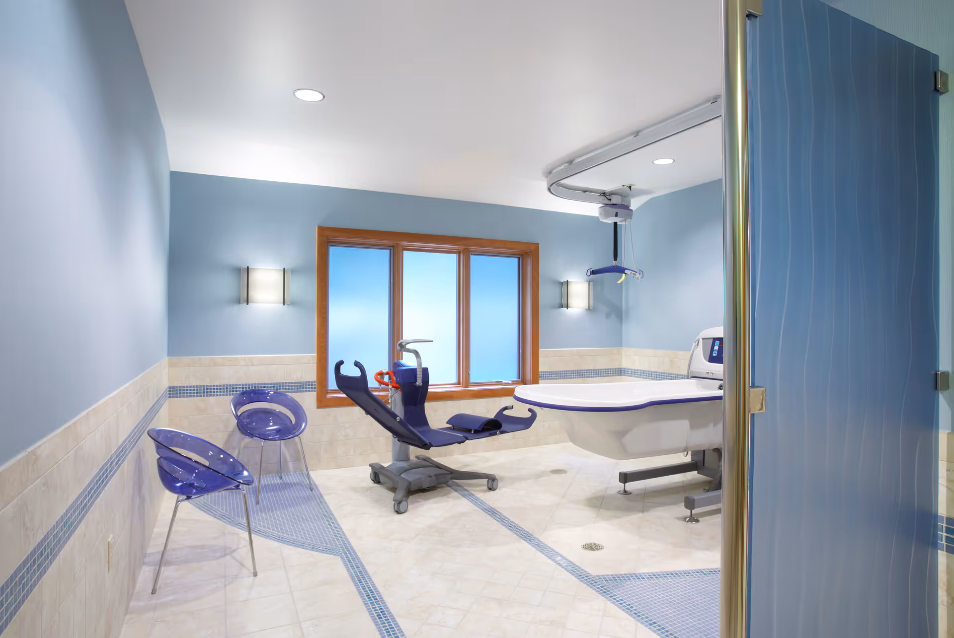 Accessible bathroom with ceiling lift over a large tub and blue walls.
