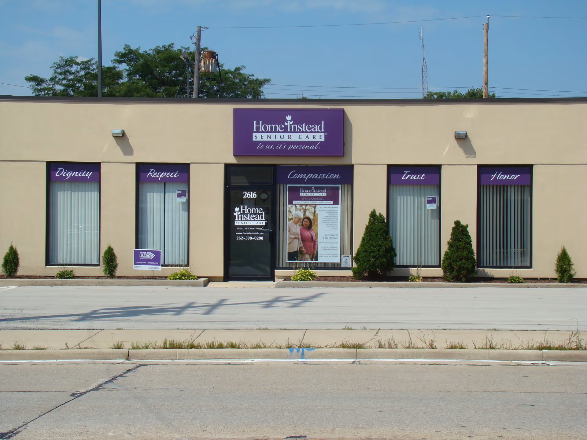 Exterior view of a beige building with Home Instead Senior Care signage and windows.